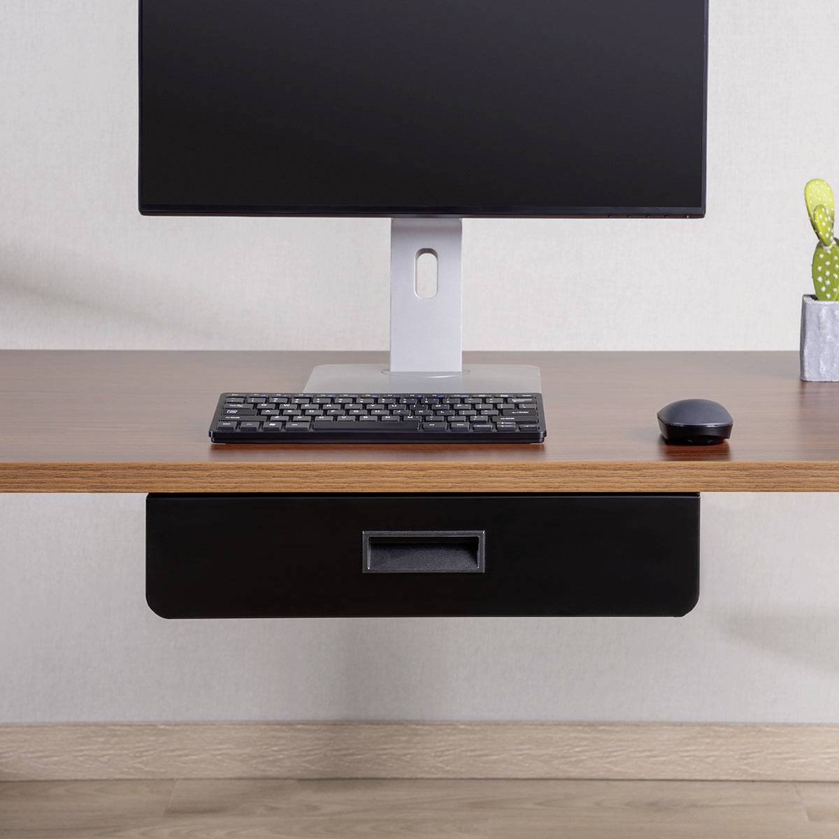 Moderna minimalistična namizna postavitev z računalniškim monitorjem, majhno rastlino in brezžično miško na leseni površini pred enobarvnim ozadjem.