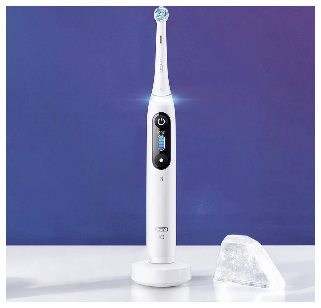 Bela električna zobna ščetka na svoji polnilni postaji na modrem ozadju, z majhno ledeno kocko v bližini, ki poudarja svežino.