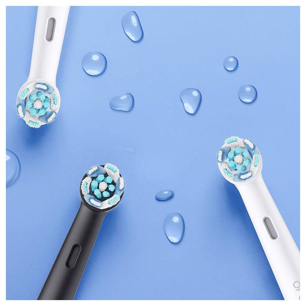 Trije električni nastavki za zobno ščetko z modro in belo ščetinasto razporejenimi v krogu na modri površini z vodnimi kapljicami.