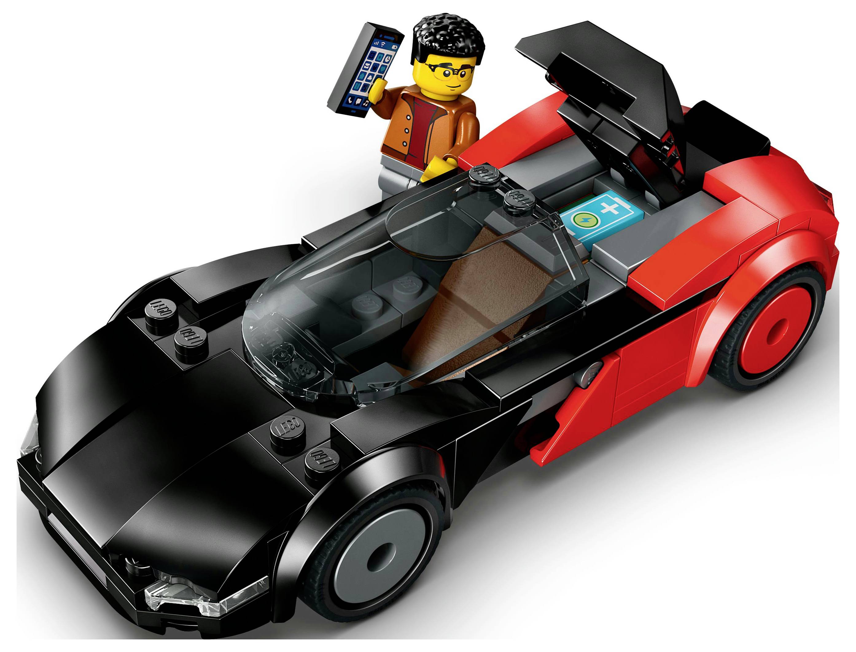 Figura LEGO z očali stoji poleg črno-rdečega modela športnega avtomobila ter drži majhno napravo. Avtomobil ima aerodinamično obliko.