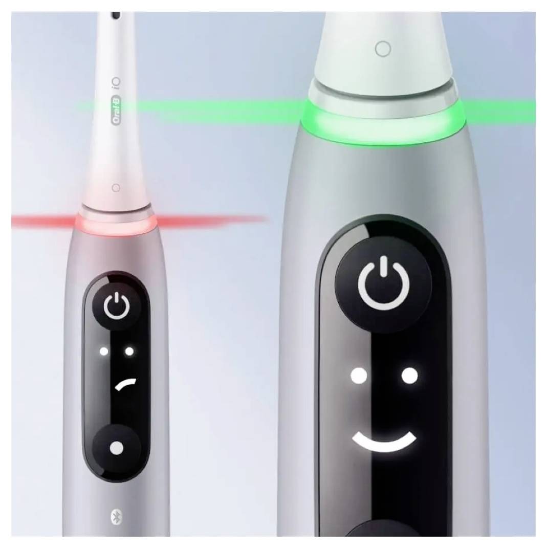 Električne zobne ščetke z digitalnimi zasloni: ena prikazuje rdeč namršten obraz, ki nakazuje težavo; druga zeleni nasmeh, ki nakazuje pravilno delovanje.