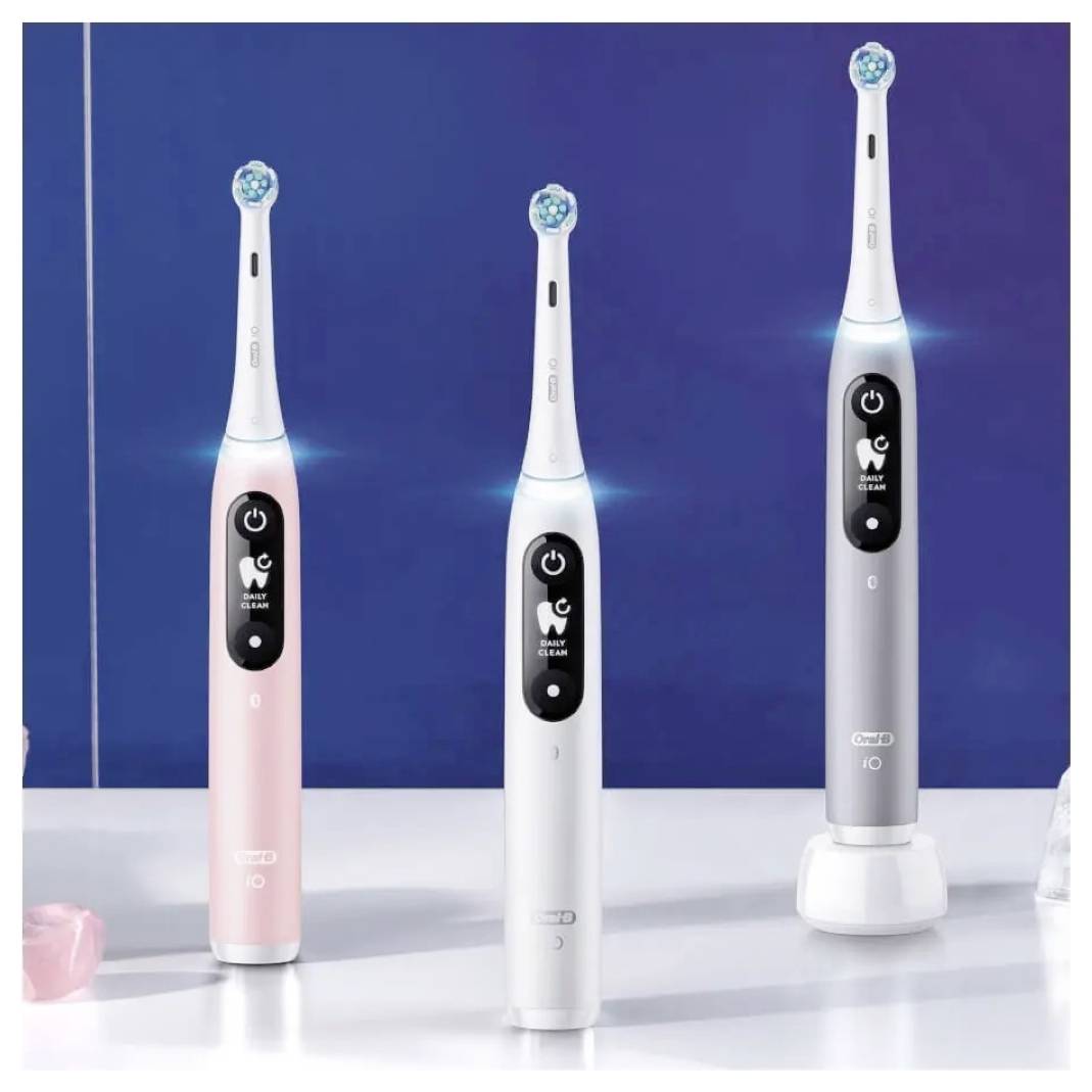 Trije električni zobne ščetke v roza, beli in srebrni barvi z gumbi za vklop in ikonami na zaslonu, postavljeni na modrem ozadju.