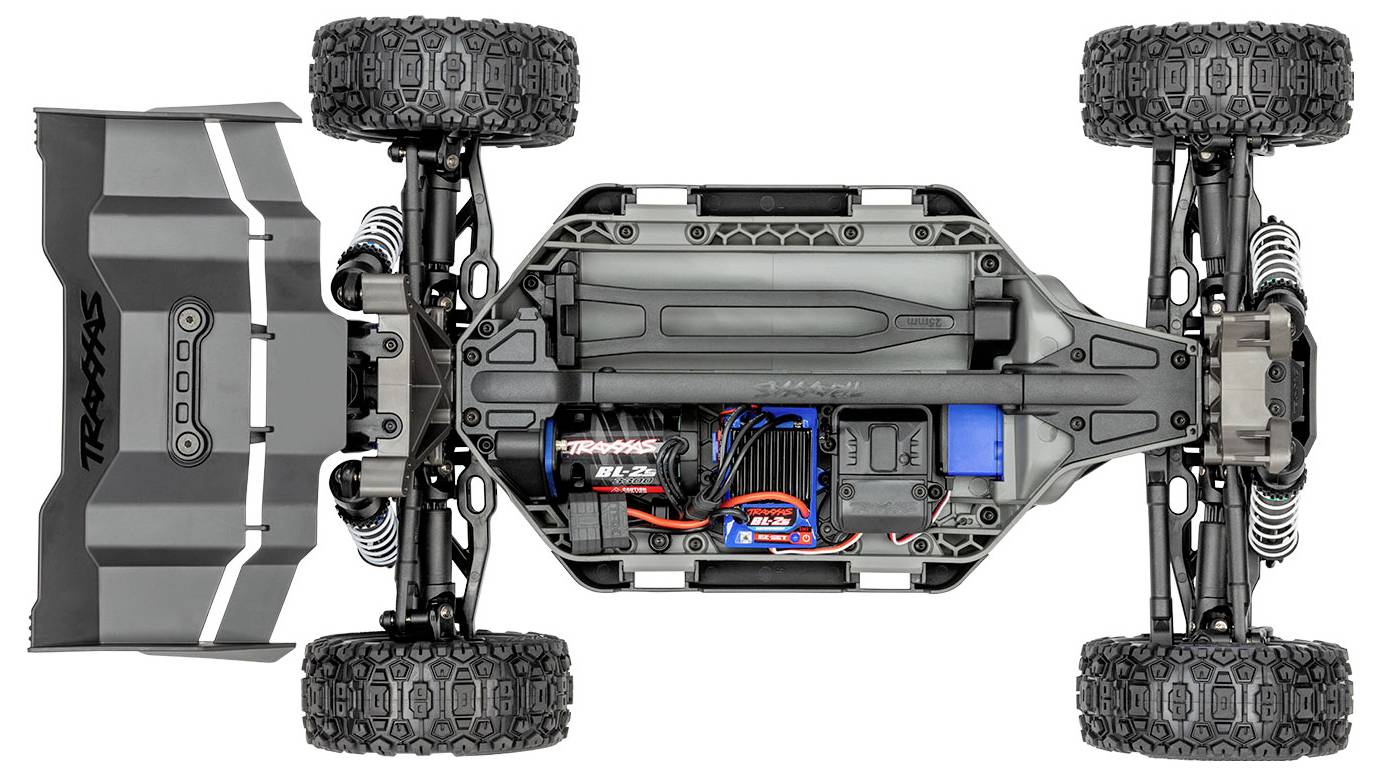 Pogled od spodaj na Traxxas RC avtomobil, ki prikazuje šasijo, baterijo, motor in sistem vzmetenja ter poudarja podrobno inženirstvo.