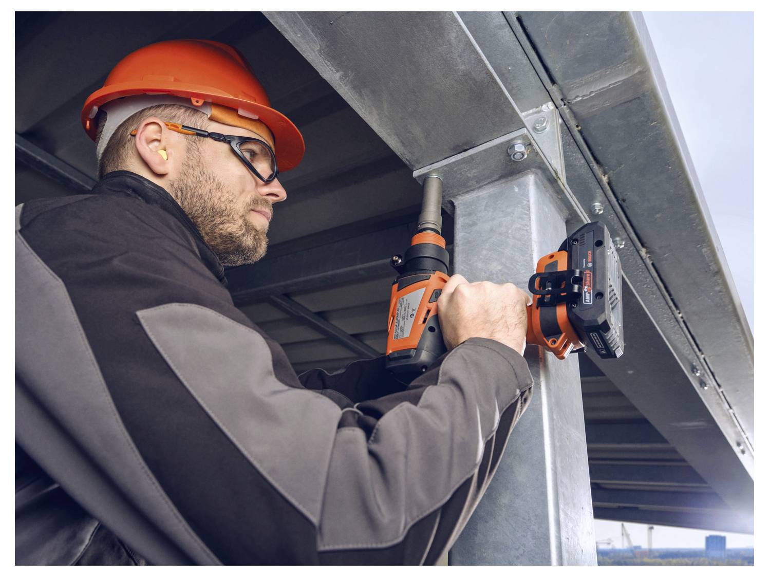 Gradbenika v zaščitni opremi vrtalni stroj za varno in natančno pritrditev kovinskega nosilca na gradbiščem.