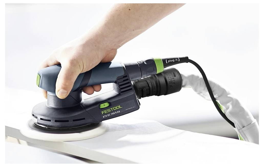 Oseba uporabi brusilnik Festool ETS EC 150/3 za glajenje lesene površine. Orodje je priključeno na cev za odvajanje prahu.