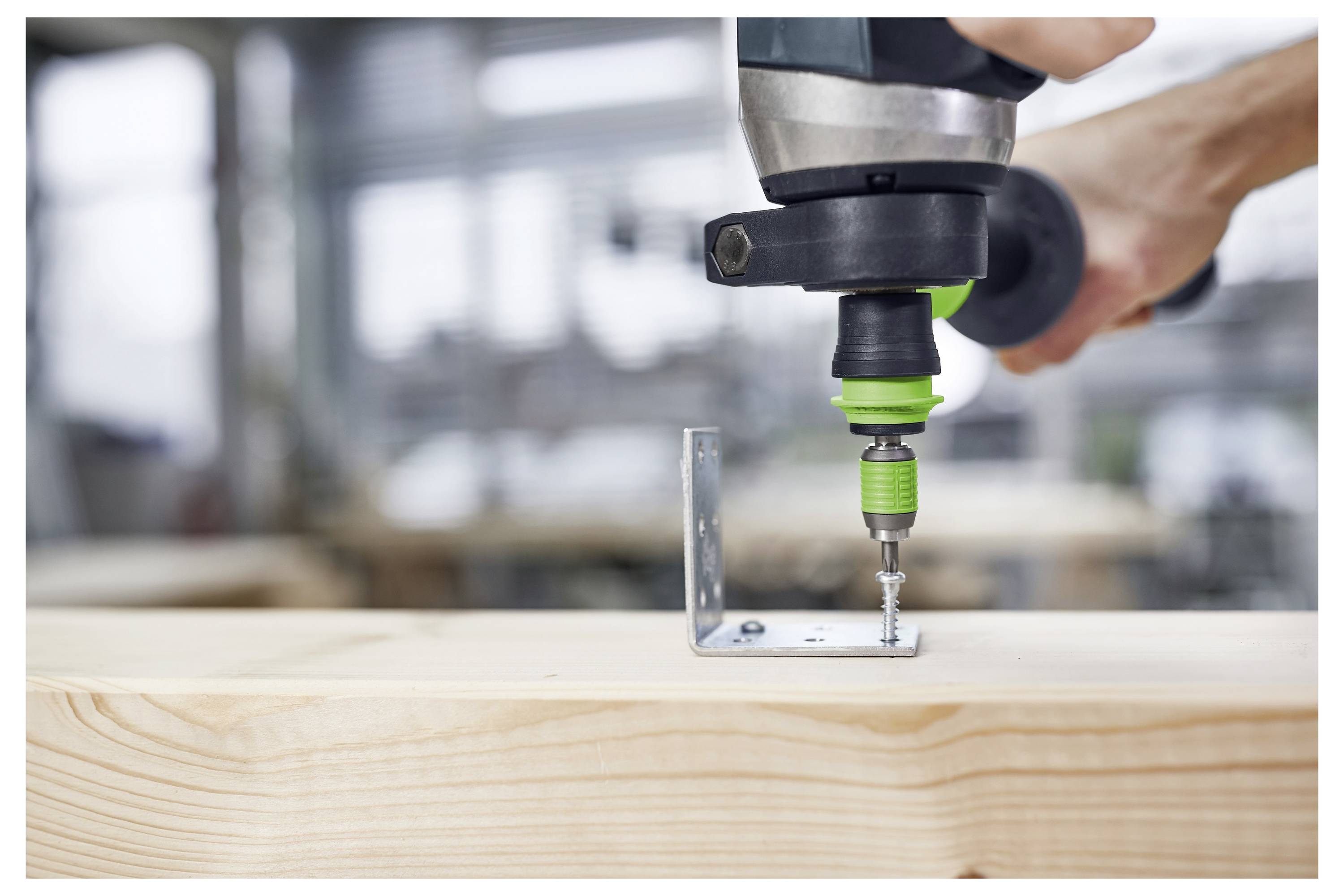 Oseba upravljajo Power Drill, ki vijak kovinasto nosilec v leseno desko, znotraj delavnice.