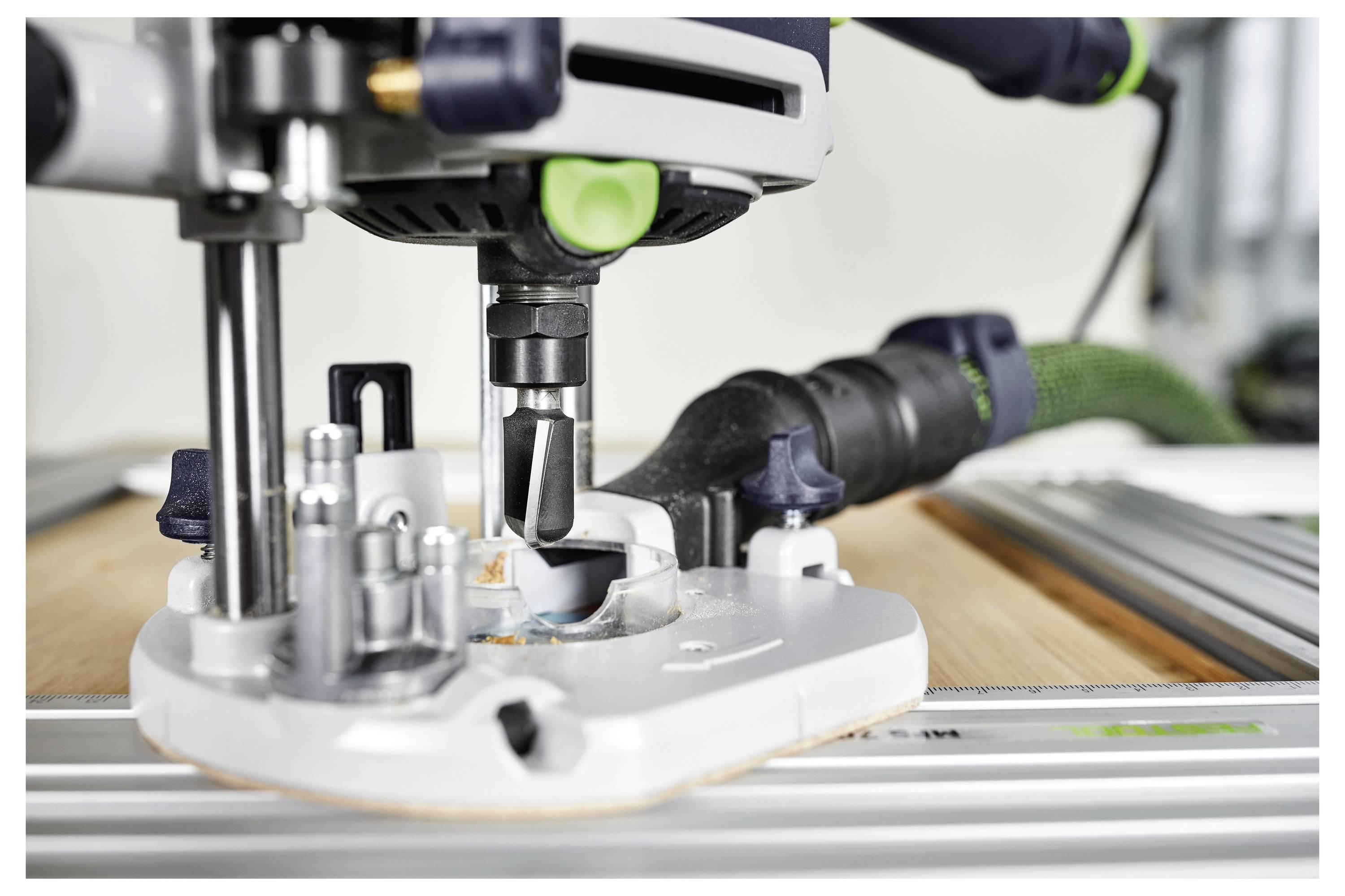 Detaljni posnetek delovnega usmerjevalnika pri delu na kos lesa, s poudarkom na vrteči se nastavku, ki naredi natančne reze.