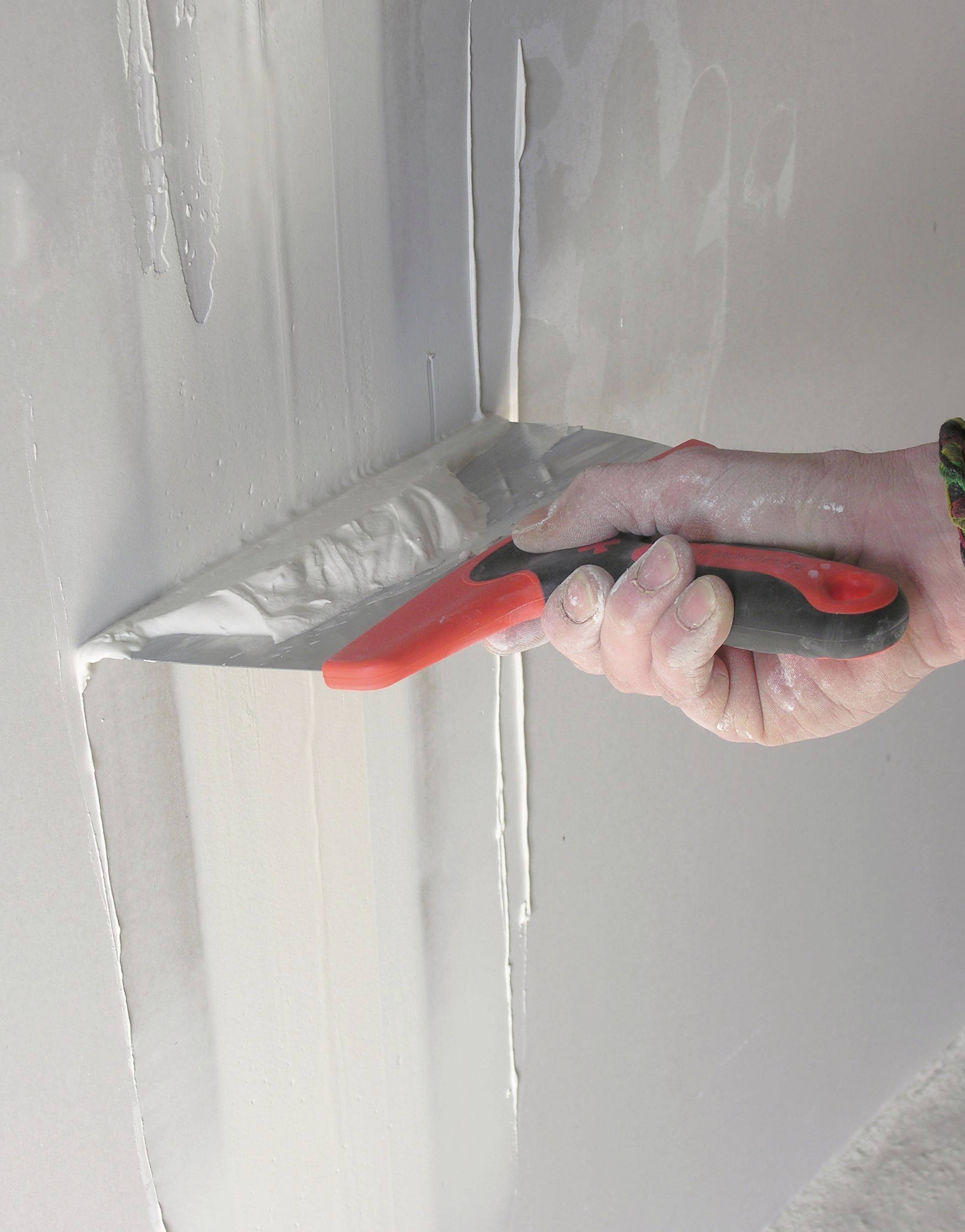 Roka z nožem za kit, ki nanaša ali gladi skupni premaz čez stik na stenski površini med končno obdelavo suhomontažnih plošč.