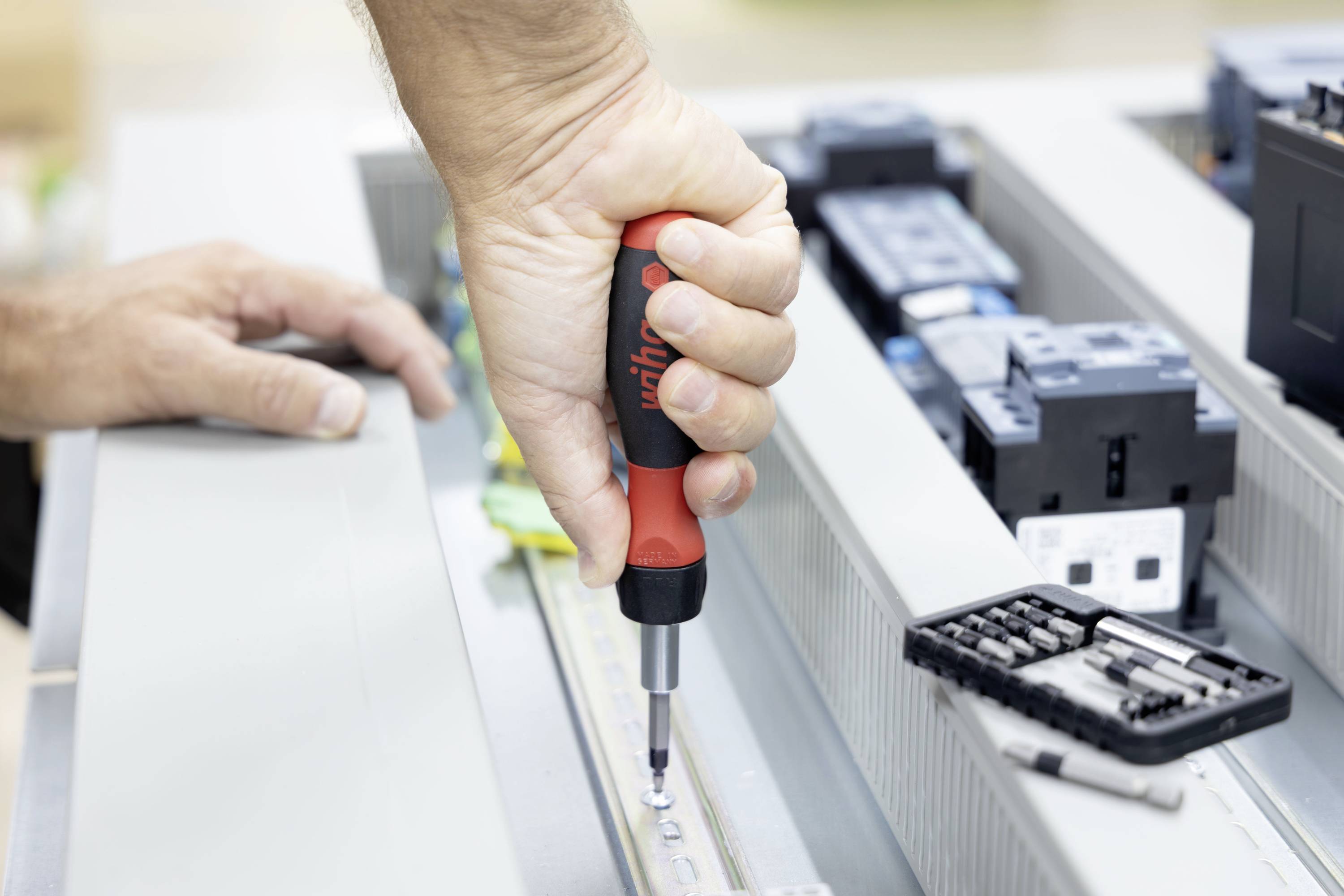 Oseba uporablja izvijač, da zategne vijak v notranjosti odprte elektronske naprave med montažo ali popravilom.