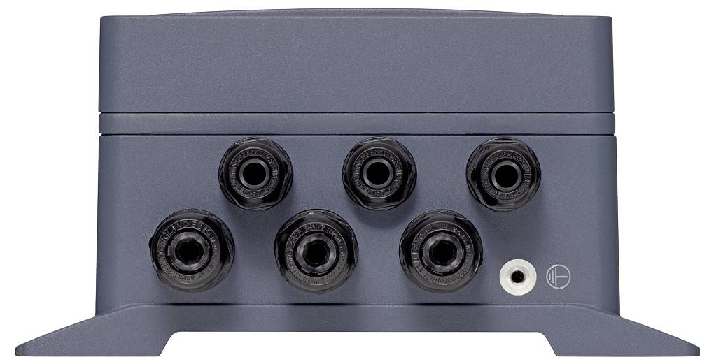 Frontalni pogled sive elektronske naprave z šestimi krožnimi črnimi vhodnimi vtičniki in enim manjšim belim portom na sprednjem panelu.