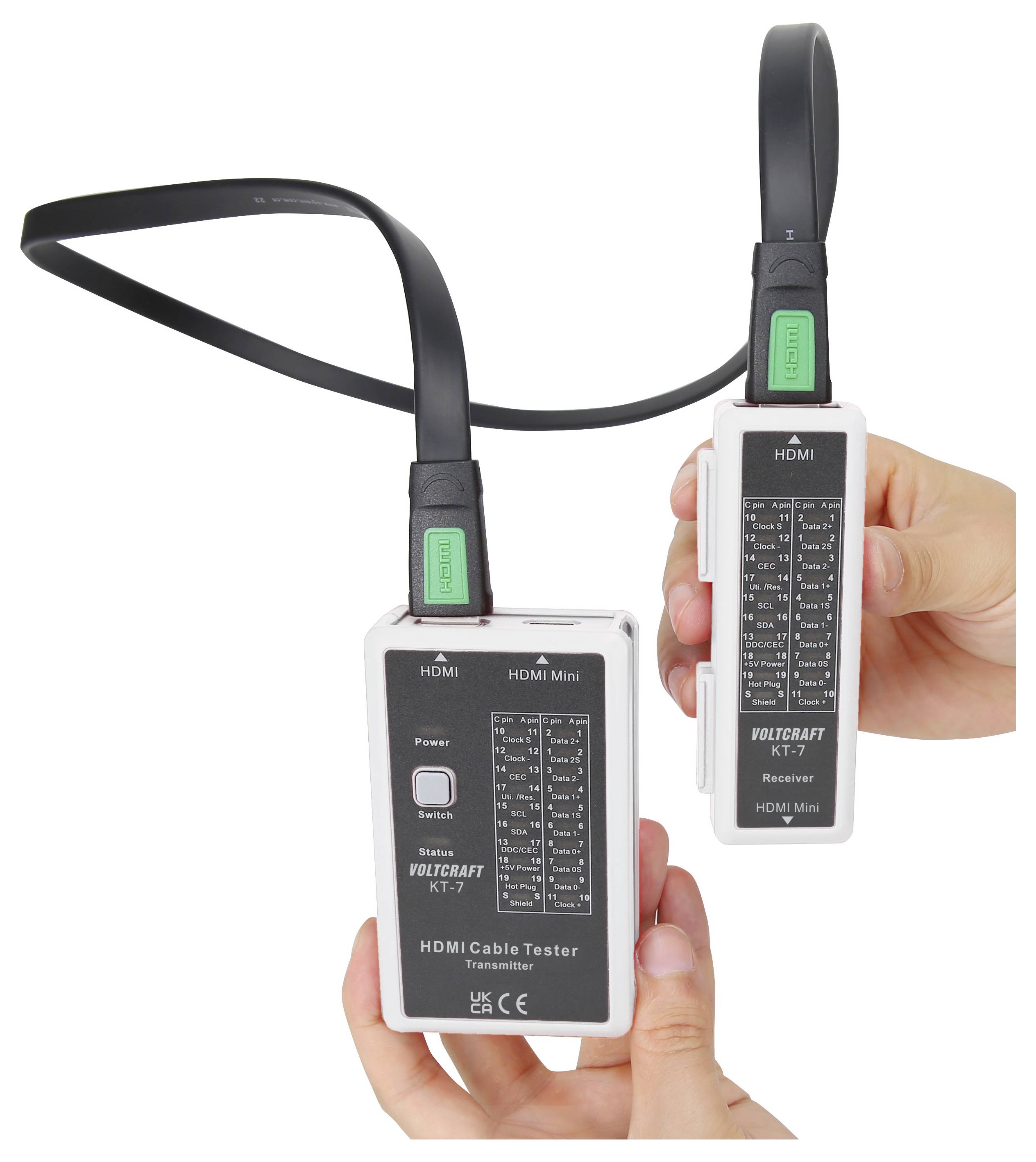 Roke, ki držijo VOLTCRAFT KT-7 tester HDMI kablov, oddajnik in sprejemnik, povezana s kablom, z oznako priključkov/stanja testa na vsaki enoti.