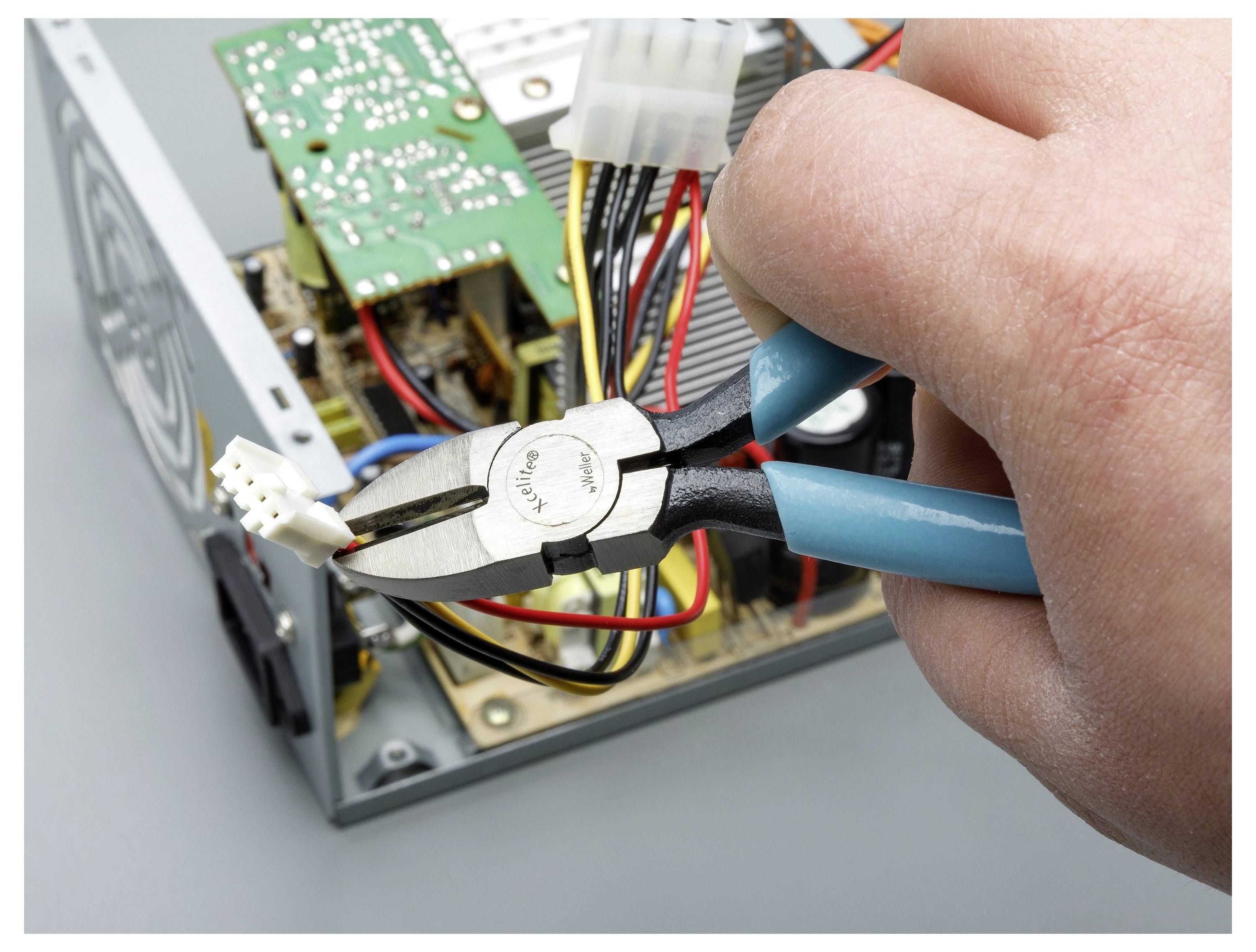 Roka z klešči seka žico znotraj odprte elektronske naprave ali računalnika.