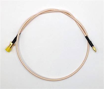 Navitljani bakreni koaksalni kabel z zlato obarvanaimi priključki na obeh koncih pred enostavnim belim ozadjem.