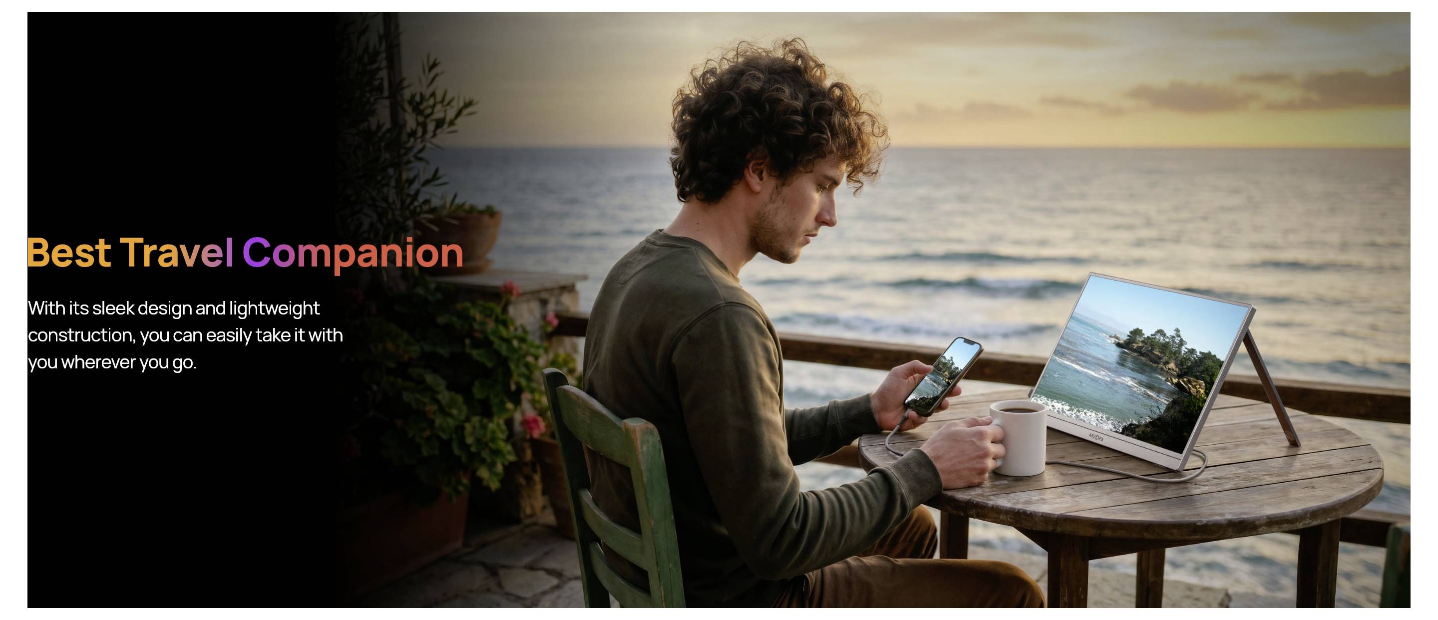 Moški s prenosnim računalnikom in telefonom pri mizici ob morju poleg majhnega prenosnega zaslona, z oglasnim besedilom »Najboljši potovalni spremljevalec«, ki promovira lahko, potovanju prijazno napravo.