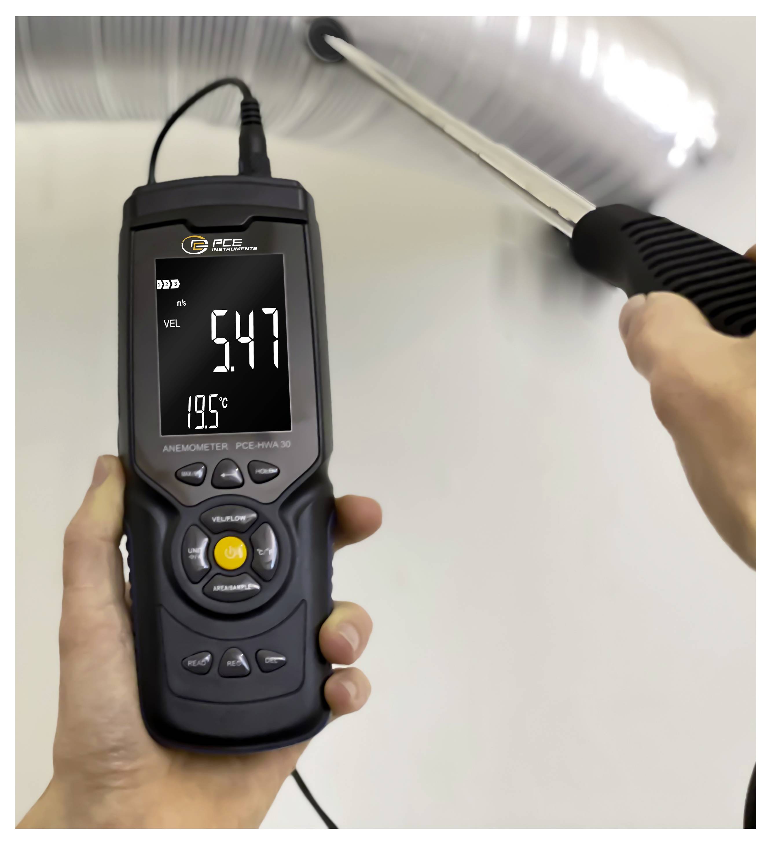 Prenosni anemometer, ki meri hitrost zraka iz stropu izpusta, prikazuje 5,47 in 19,7 °C na zaslonu.