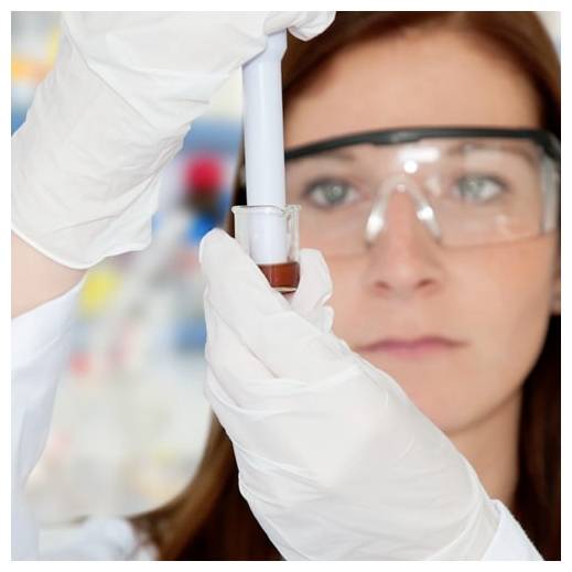 Znanstvenik v rokavicah in zaščitnimi očali pregleda majhno epruveto s pipeto v laboratoriju.
