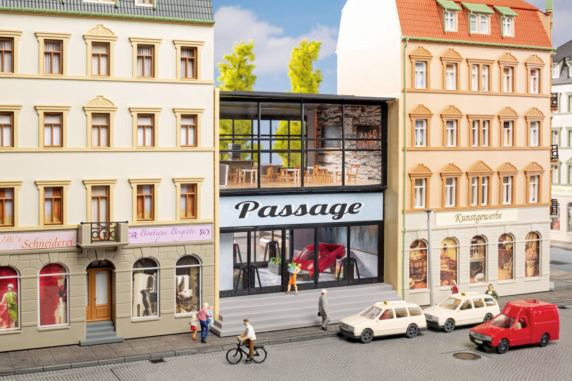 Model mestne ulice z ozko ograjenim prostorom ob moderni "Passage" trgovini v etalažah, pešci, kolesarji in parkirani avtomobili.