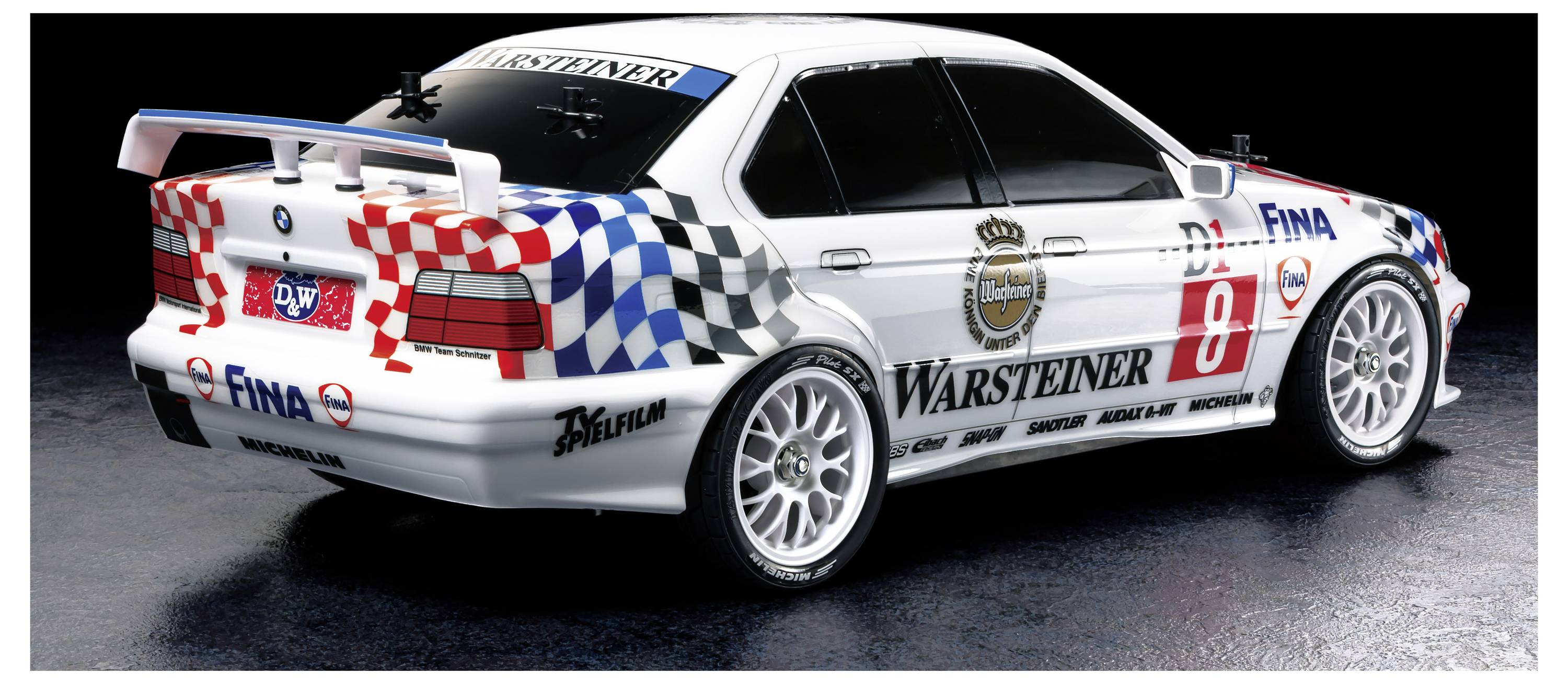 Bela tekaška dirkalnik BMW z rdeče-modro kvadratno barvo, logotipoma FINA in Warsteiner, pogled z zadnje strani na temnem ozadju.
