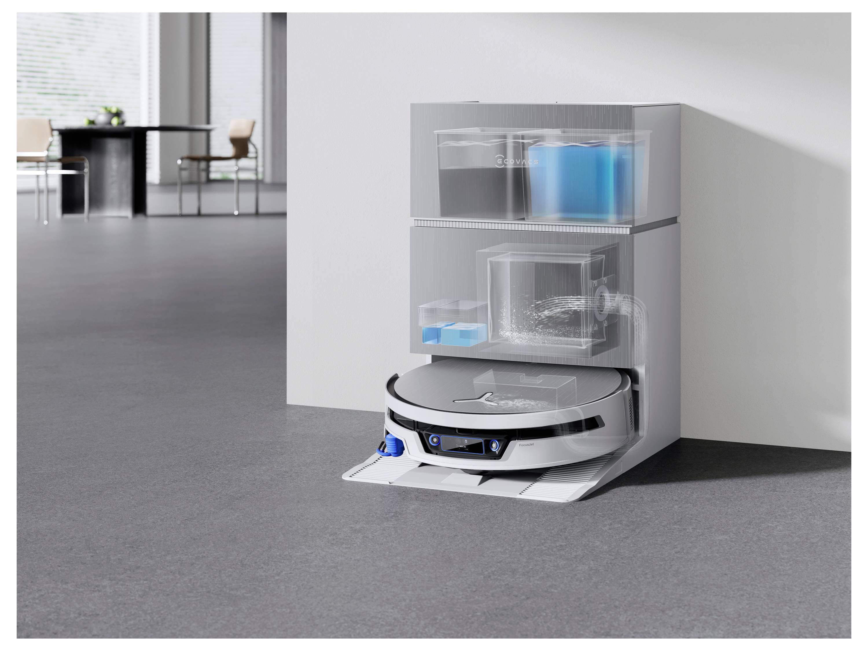 Robotski sesalnik priklučen na polnilno postajo ob steni z vodnimi rezervoarji in čistilnimi moduli v sodobni pisarniški sobi.