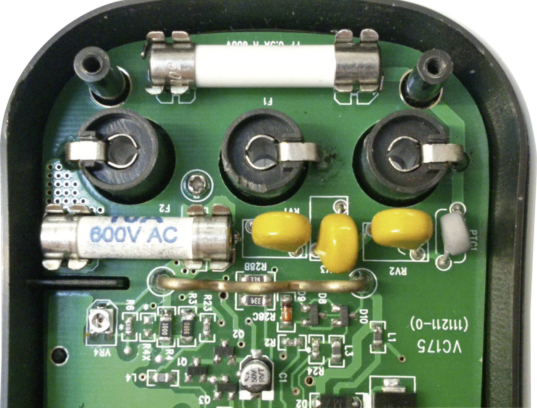 Elektronska plošča z več varovalkami, rumenimi kondenzatorji in črnimi tuljavami. Na eni varovalki je viden napis '800V AC'.