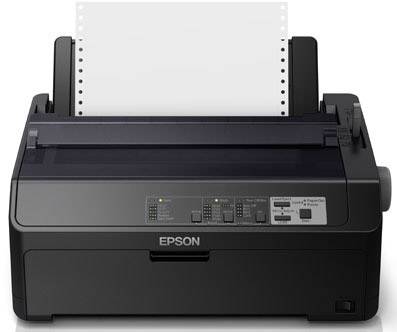 Črn iglični tiskalnik znamke Epson stoji na mizi. List neskončnega papirja je izdan iz zgornjega dela tiskalnika.