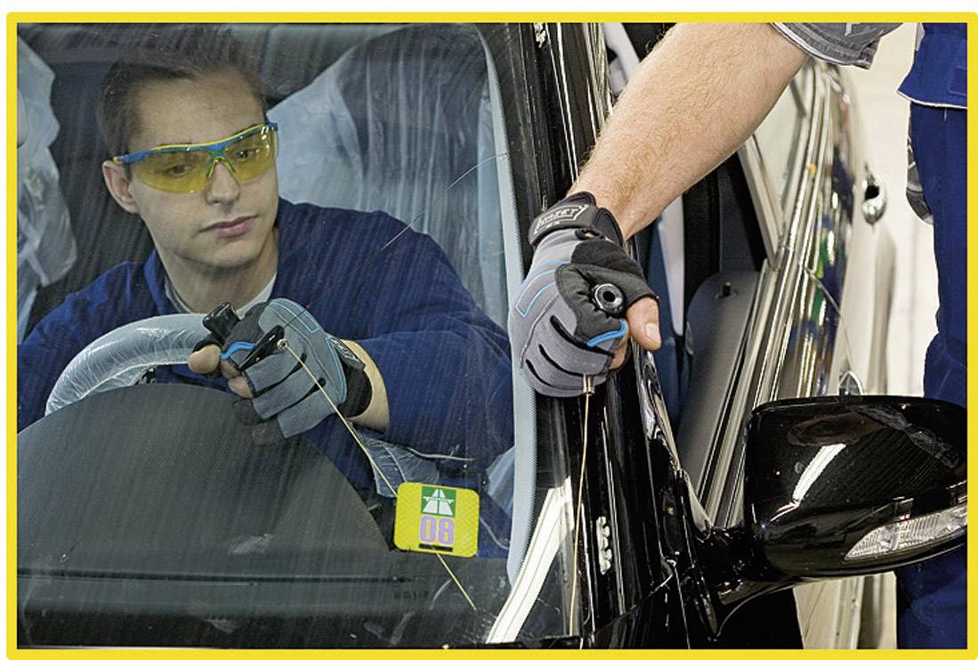 Mehanik uporablja elektronsko diagnostično napravo za preverjanje delovanja avtomobilskega stekla. Možakar sedi v avtomobilu.