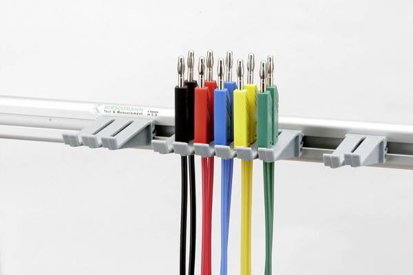 Färgglada krokodilklämmor i blått, rött, svart, gult och grönt hänger på ett metallställ med jämna mellanrum.