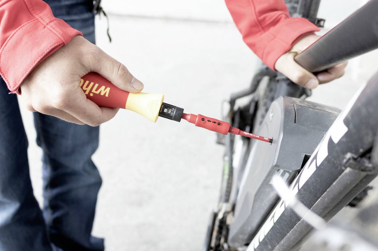 En person reparerar en cykel genom att arbeta med en skruvmejsel på en del av ramen eller hjulet.