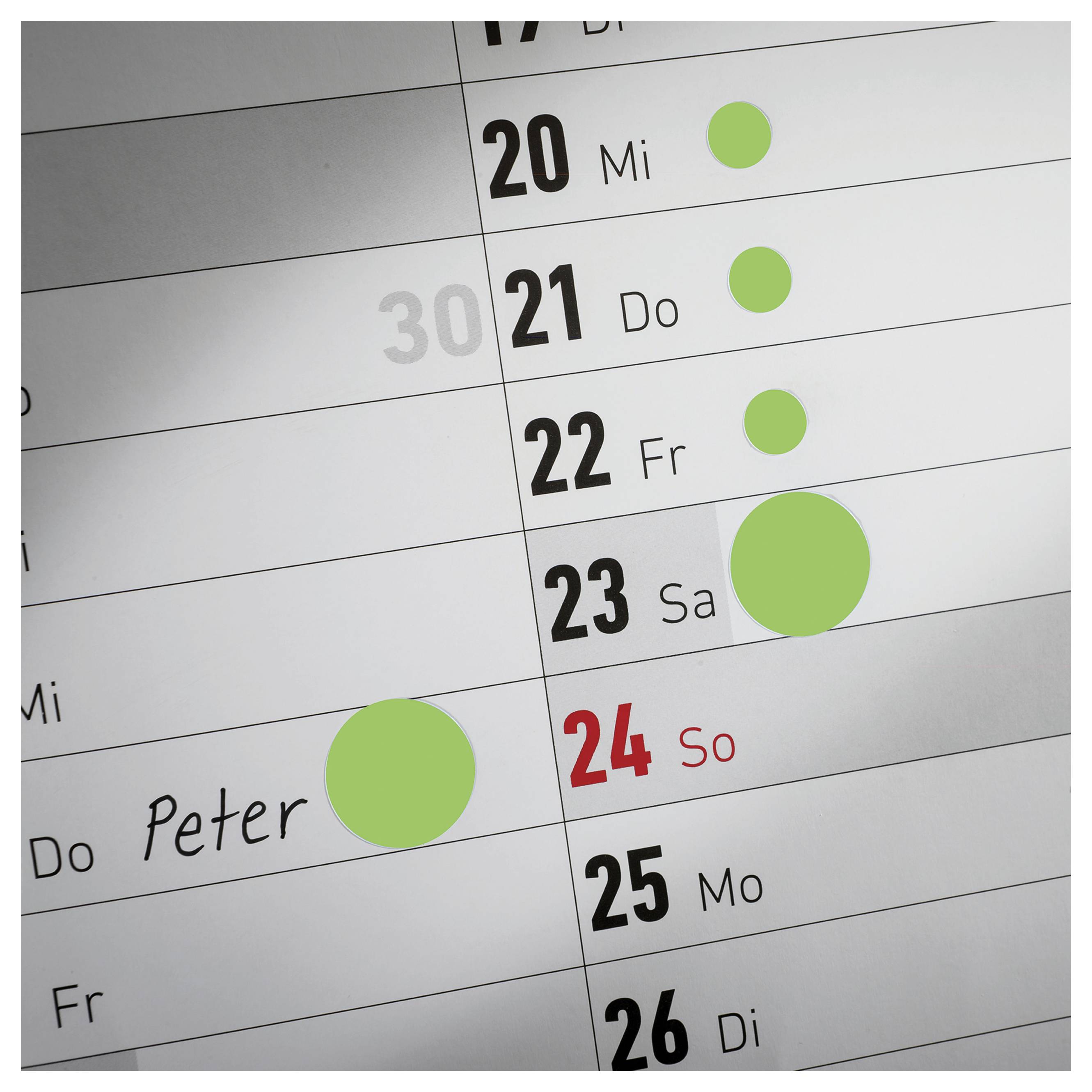 Närbild av en kalenderplan med dagarna 20 till 26; flera gröna markeringar och den röd framhävda 24:e söndagen. En träff "Peter" är inskriven.
