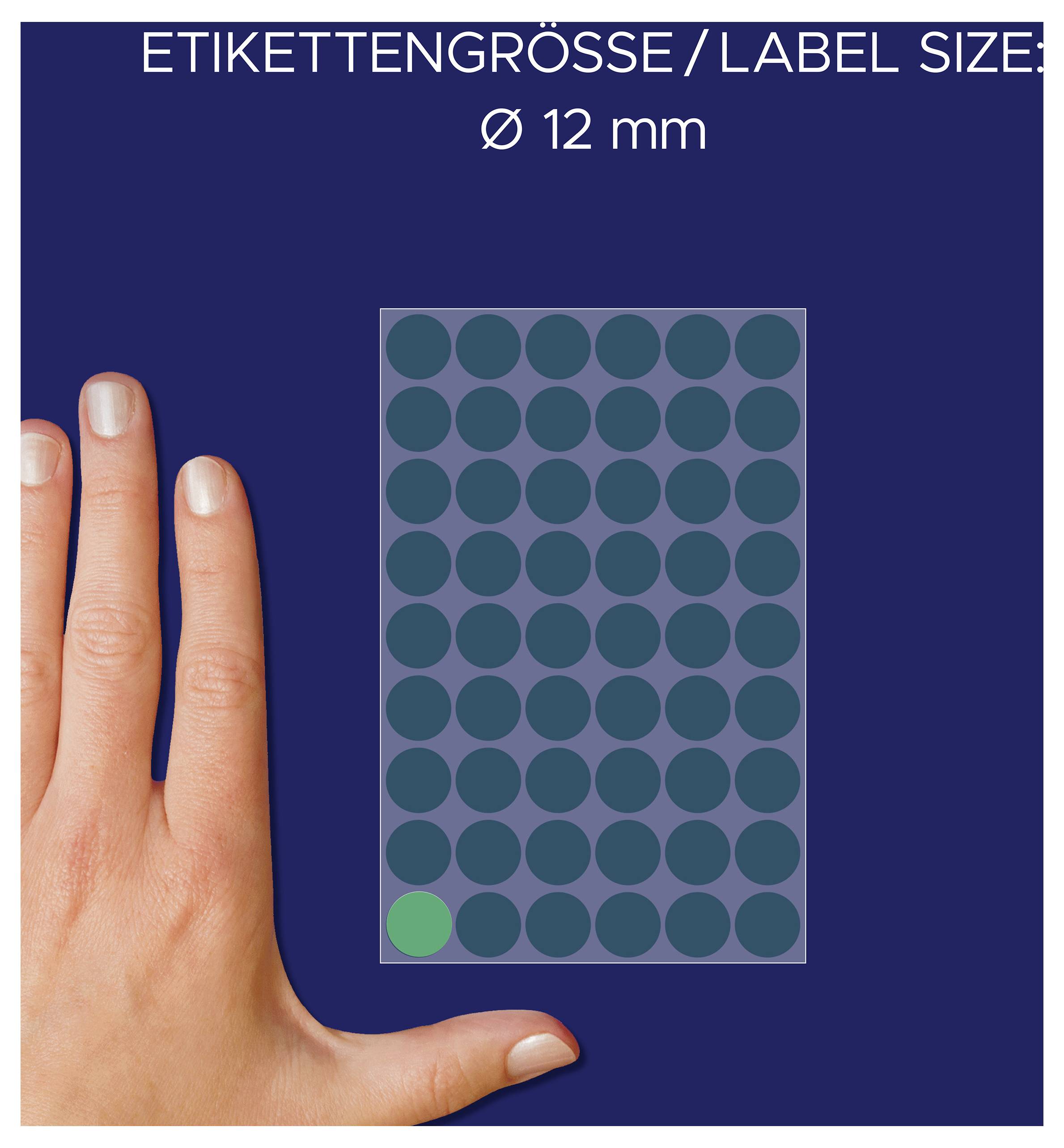 Etikettens storlek 12 mm: Hand bredvid ett ark med runda klistermärken, ett klistermärke är markerat.