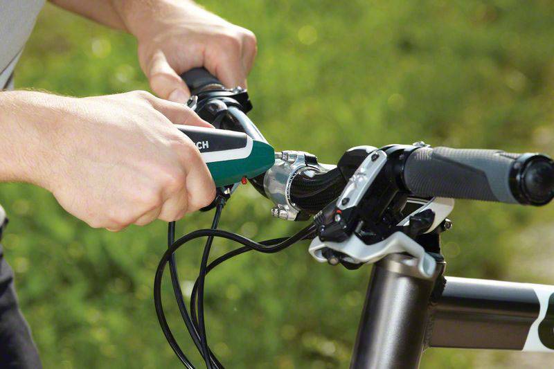 En person fäster ett nytt cykelhandtag på styret medan han/hon kontrollerar cykelmekanismen.