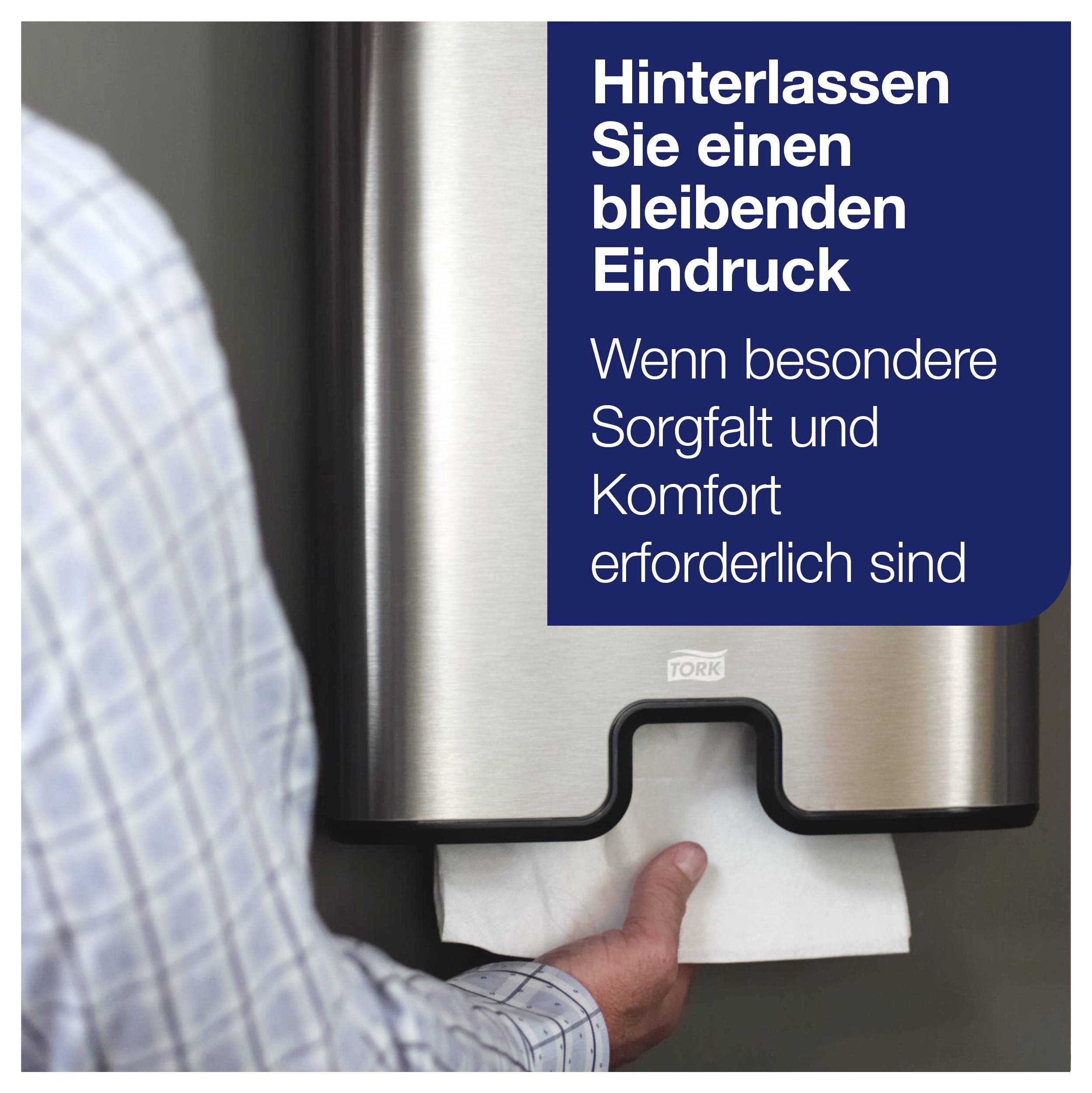Reklam för en Tork-dispenser: En hand drar ut ett pappershandtuch ur en rostfri stålsdispenser; Text: 'Lämna ett varaktigt intryck' och 'När särskild omsorg och komfort krävs'.