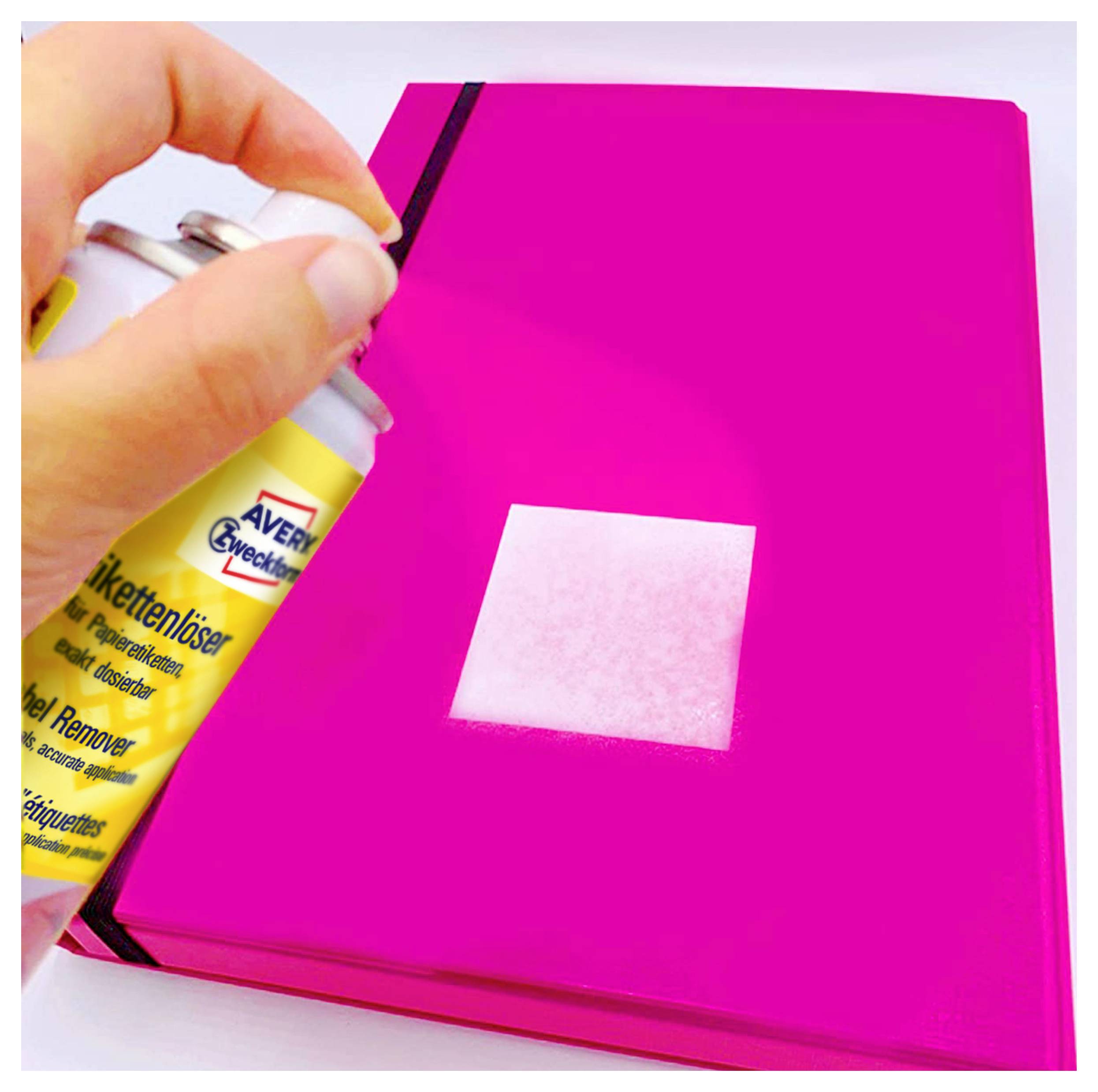 Hand sprutar etikettklistring på en ljus kvadrat på en rosa mapp eller bok.