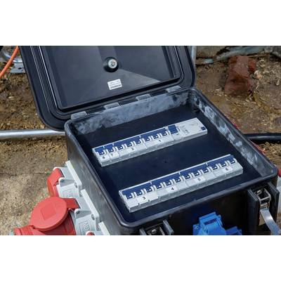 En öppen elektrisk säkringsdosa med flera blå säkringar som är numrerade. Tre röda och en blå elkontakt vid sidan.