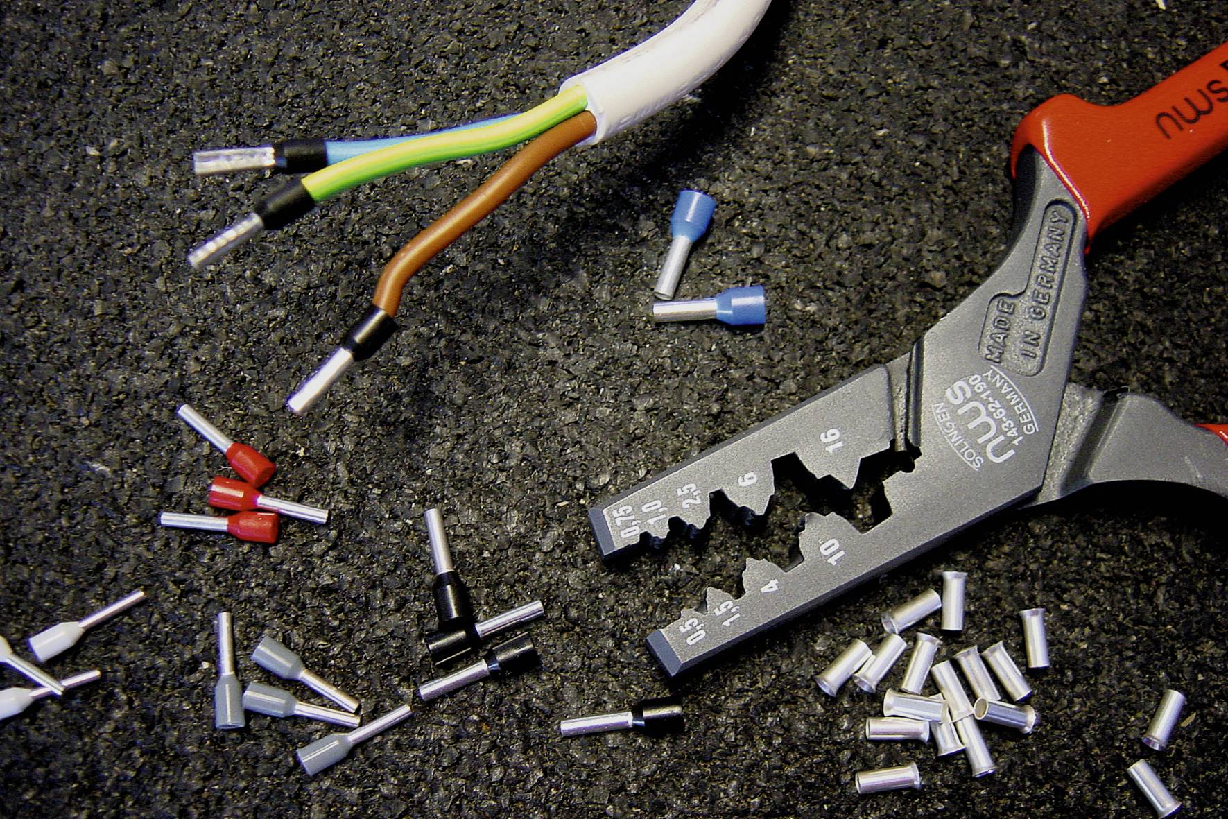 Avmantlingstång bredvid kablar och ändhylsor på en arbetsbank. Tången är lämplig för olika kabeltyper.