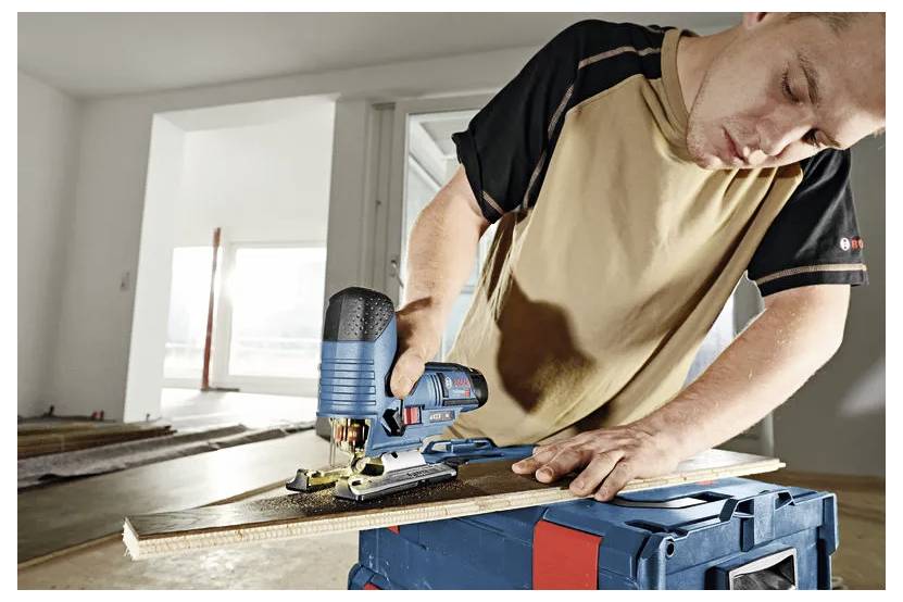 Hand som håller en Bosch trådlös slagskruvdreare för att köra en skruv in i en vit skåp- eller väggpanel.