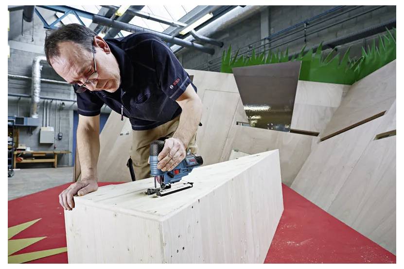 En man använder en såg för att skära ett stort träblock i en verkstad eller industriell testarea.