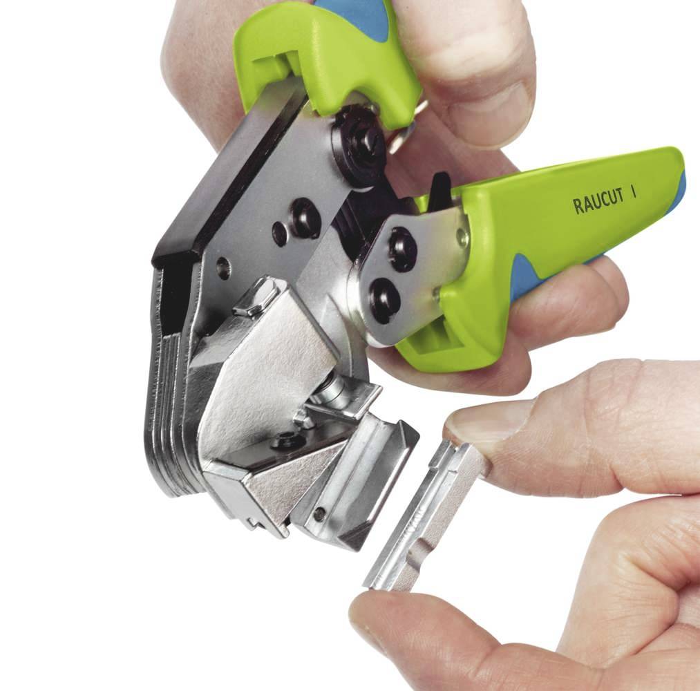 En hand håller en grön rörskärare som klipper av ett plastmrör.