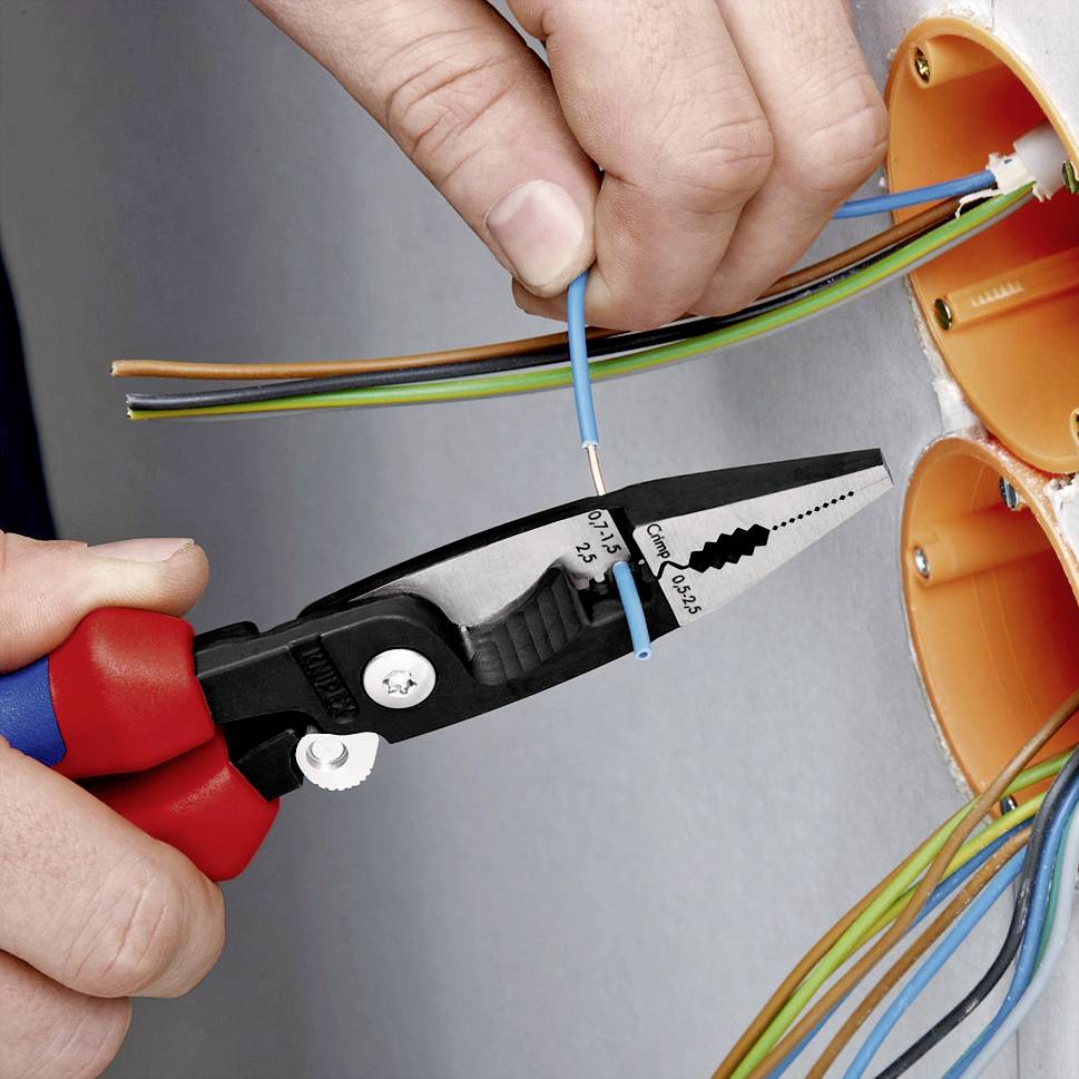 En person klipper av en kabel med en avisoleringstång. Kabeln har flera färgade ledare och installeras i en väggdosa.