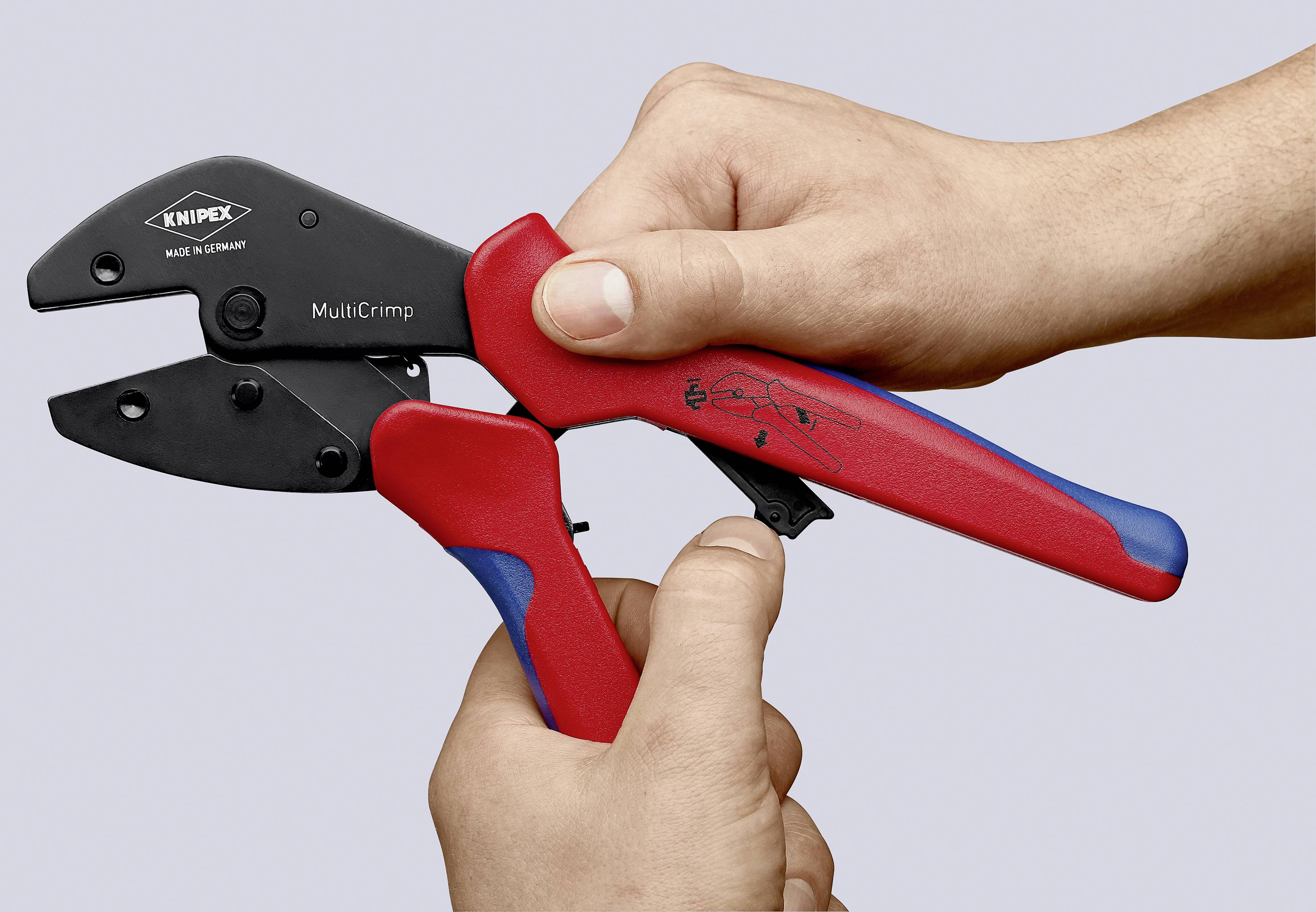 En hand håller en röd och svart crimptång från märket 'KNIPEX', modell 'MultiCrimp'.