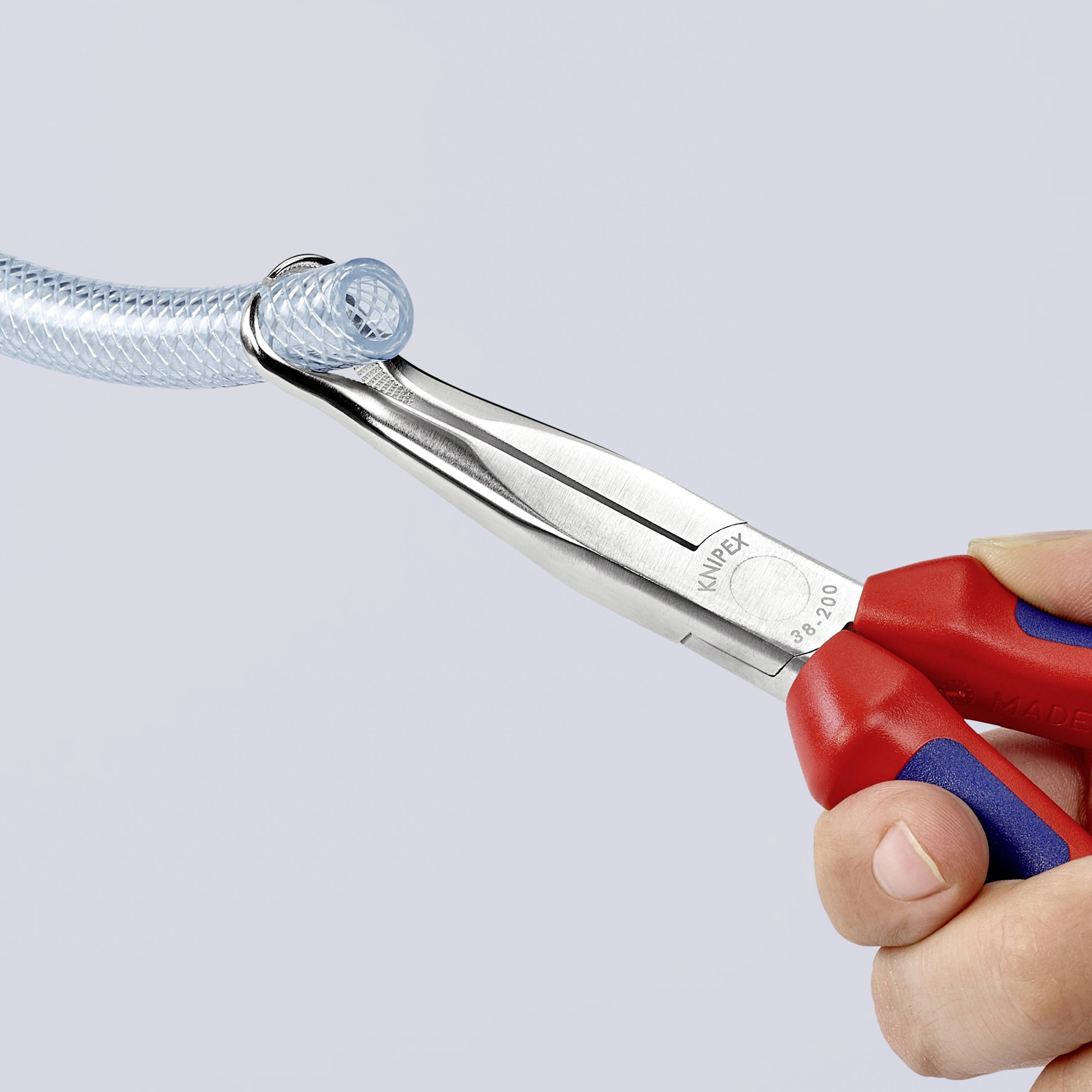 En person håller en kombinationstång med röda handtag och klipper en genomskinlig plastslang.