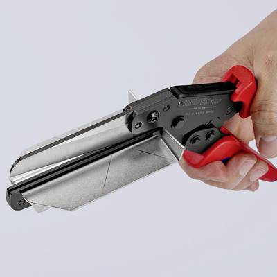En hand håller en röd och svart tång som böjer ett stycke metall. Verktyg för precisionsklippning eller böjning inom hantverksarbete.
