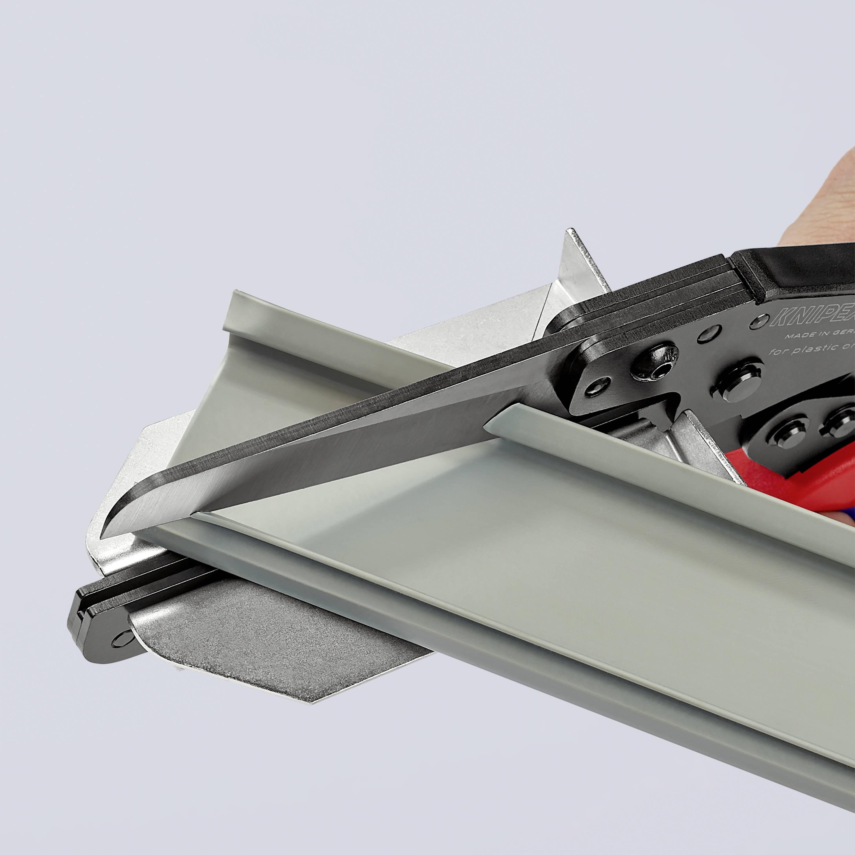 En hand använder en tygskärare för att skära ett metallstycke. Kniven glider längs metallstycket för ett precist snitt.