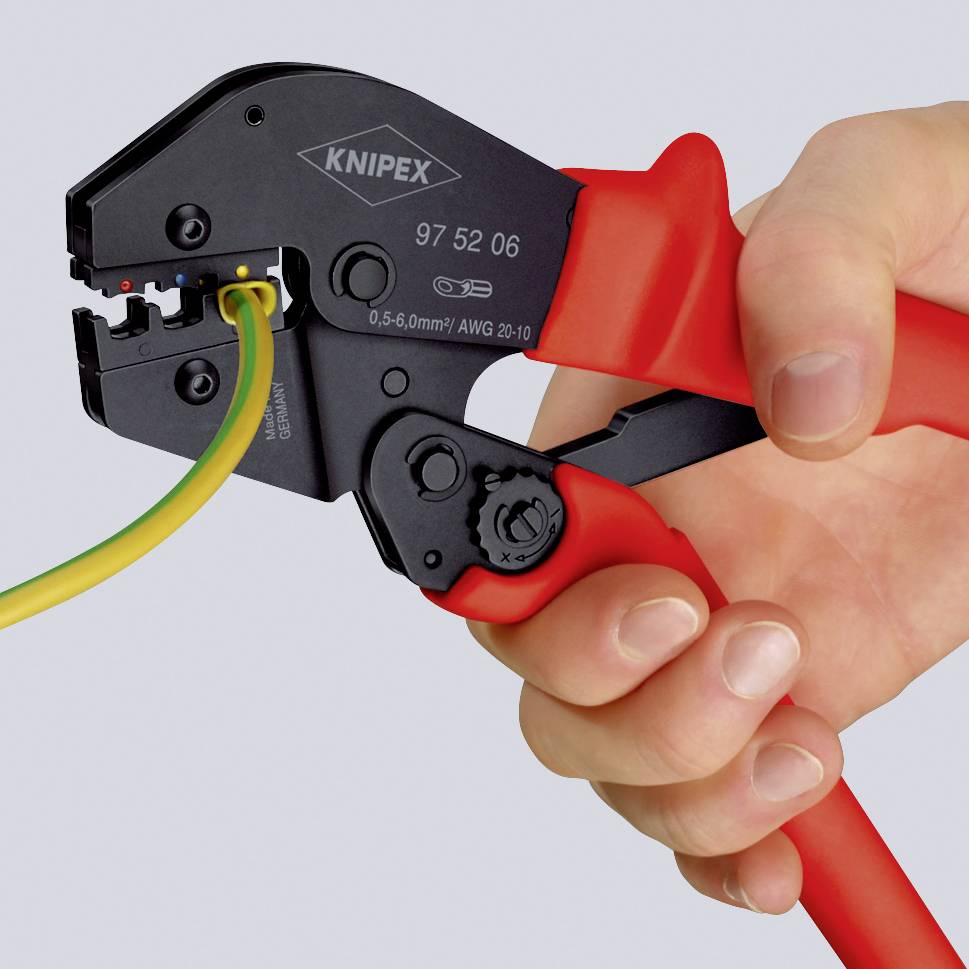 En hand håller en krympningstång från märket Knipex som bearbetar en gul-grön kabel.