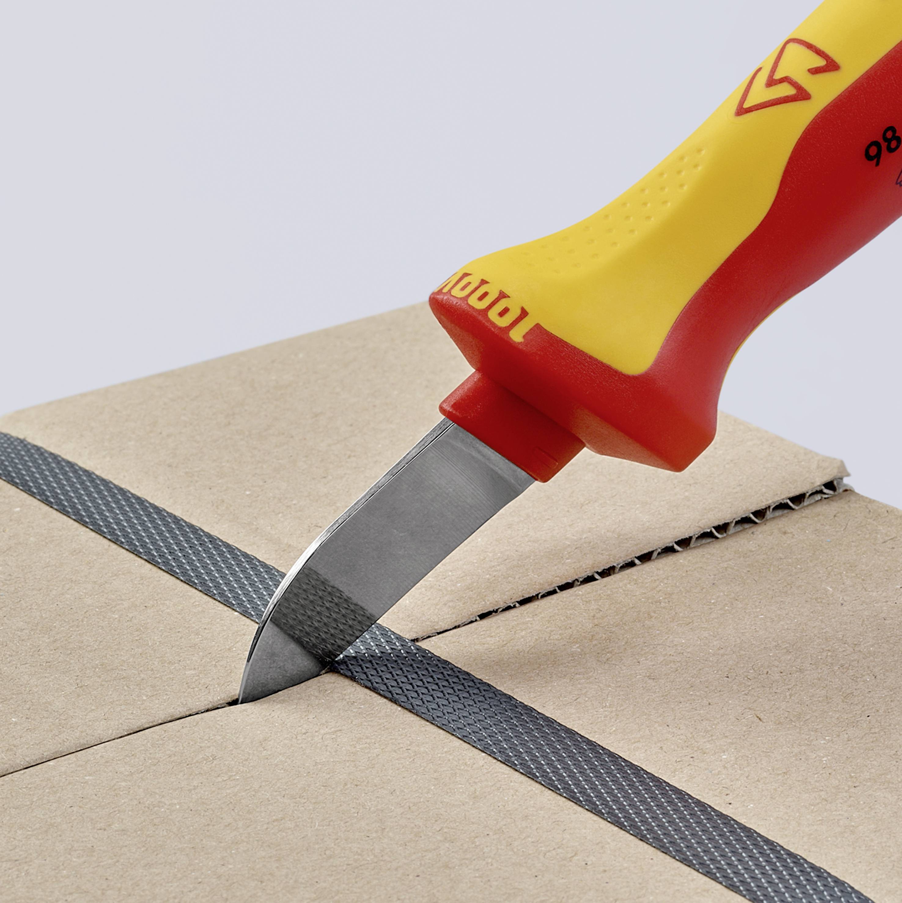 Ett gult och rött skärverktyg skär genom kartong. Kniven har ett kort, grått blad och ett ergonomiskt handtag.