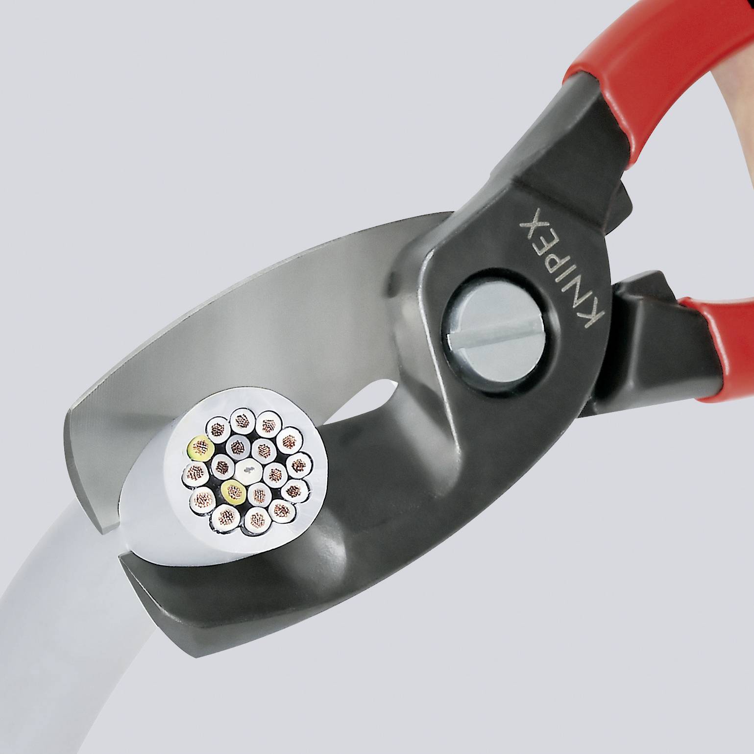 Zange klipper en kabel med flera färggranna trådar. Hon visualiserar verktygsanvändning i elektroteknikens sammanhang.