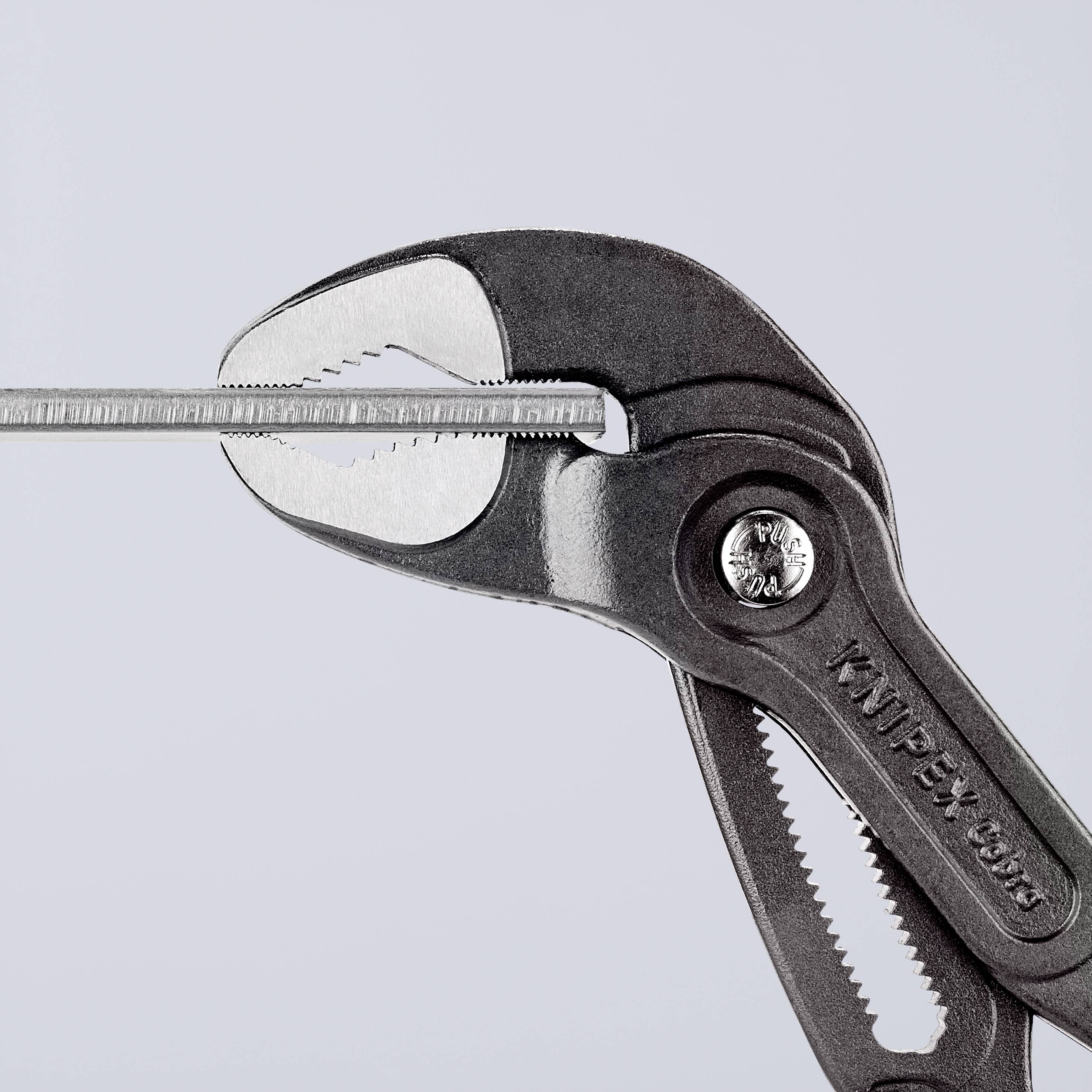 En justerbar tång med öppet käft håller en smal metallstång. På tången syns 'Knipex'.