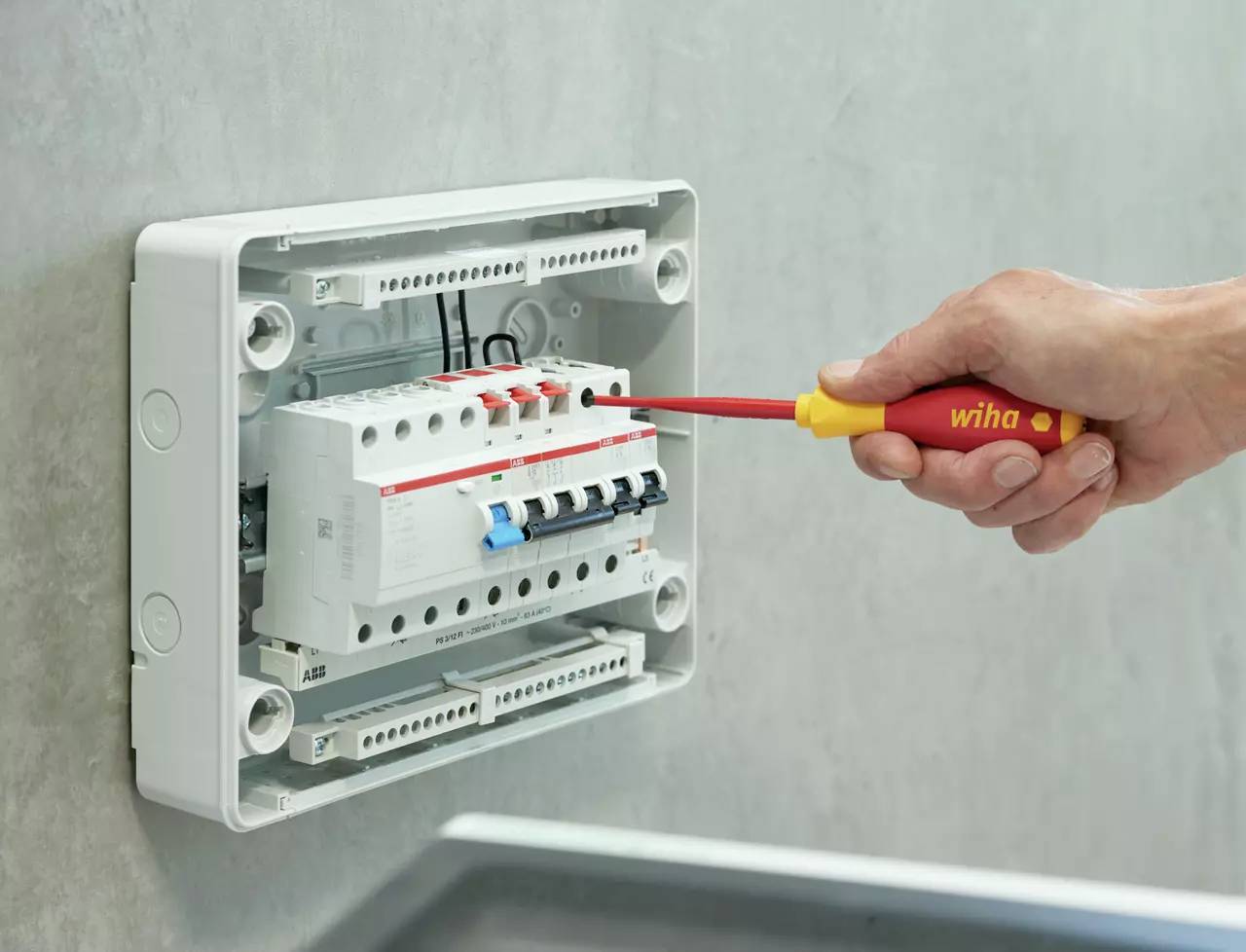 'En hand drar med en skruvmejsel omkopplaren för en elektrisk säkring i en elcentral.'