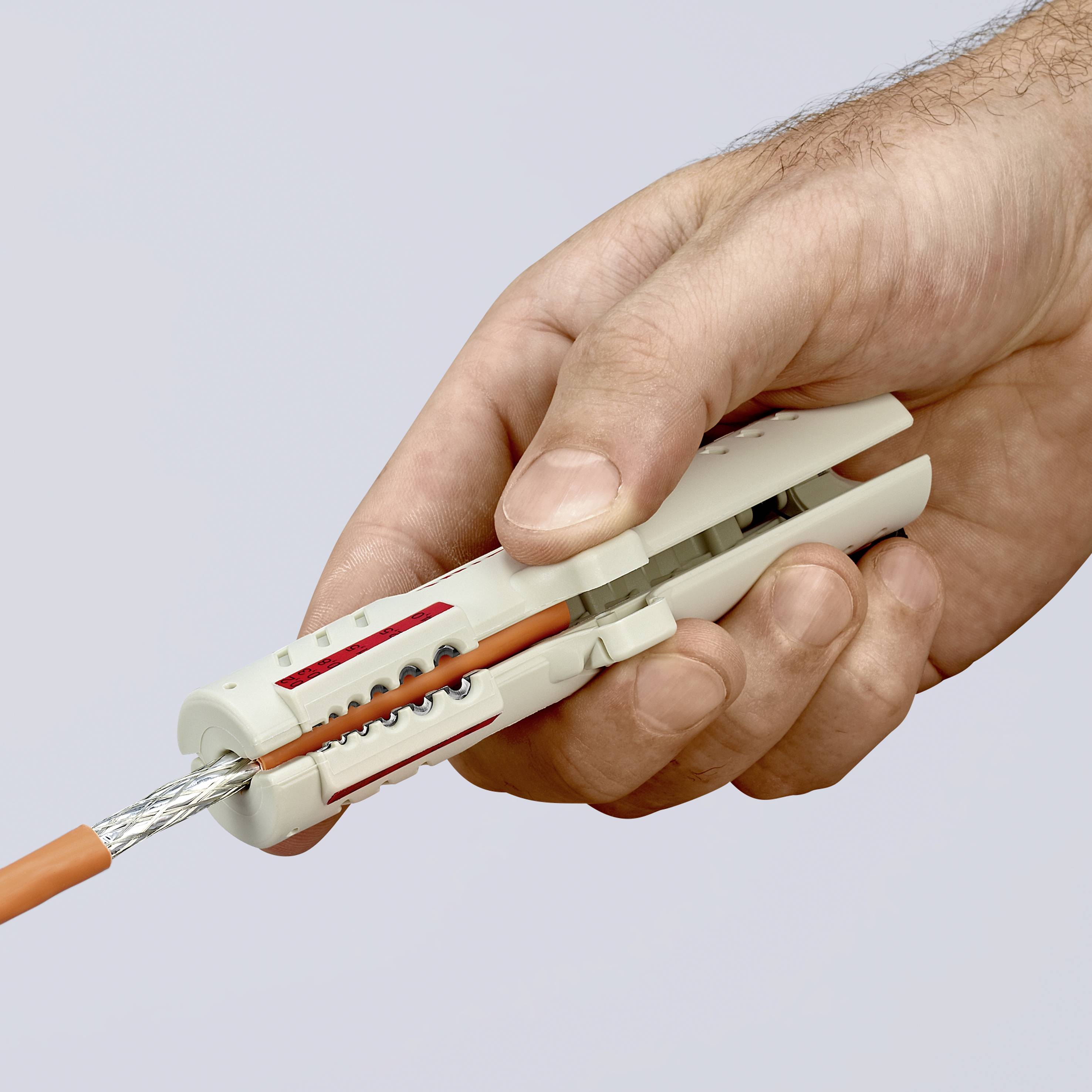 En hand håller en grå kabelsax som klipper av en orange kabel.