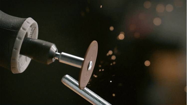 En roterande verktygsenhet med en skärskiva gnistrar medan den skär igenom en metallbult, vilket belyser verktygets precision och effektivitet inom metallarbete.